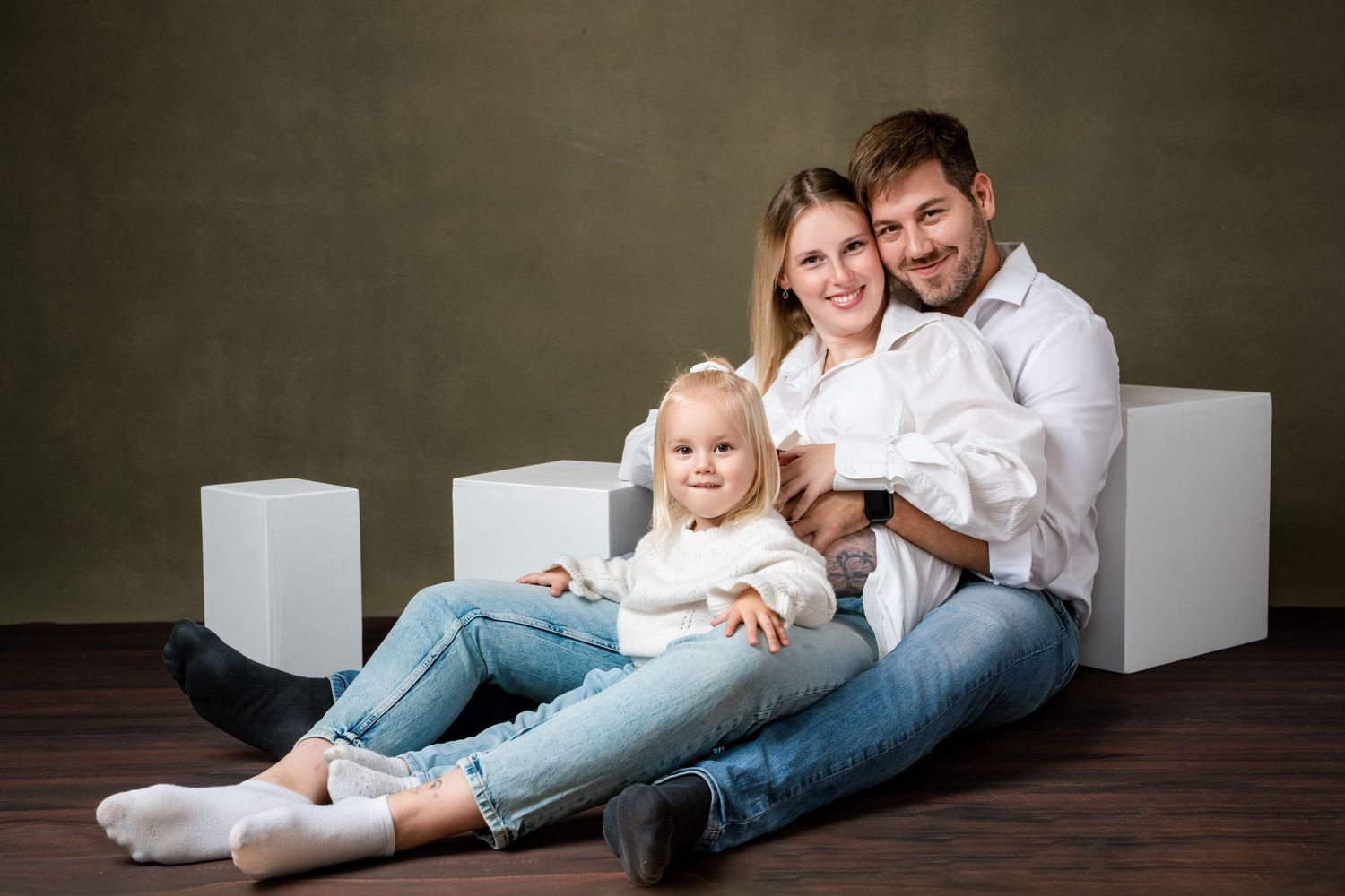 Family photo session showing playful poses with white shirts and jeans against dark backdrop.