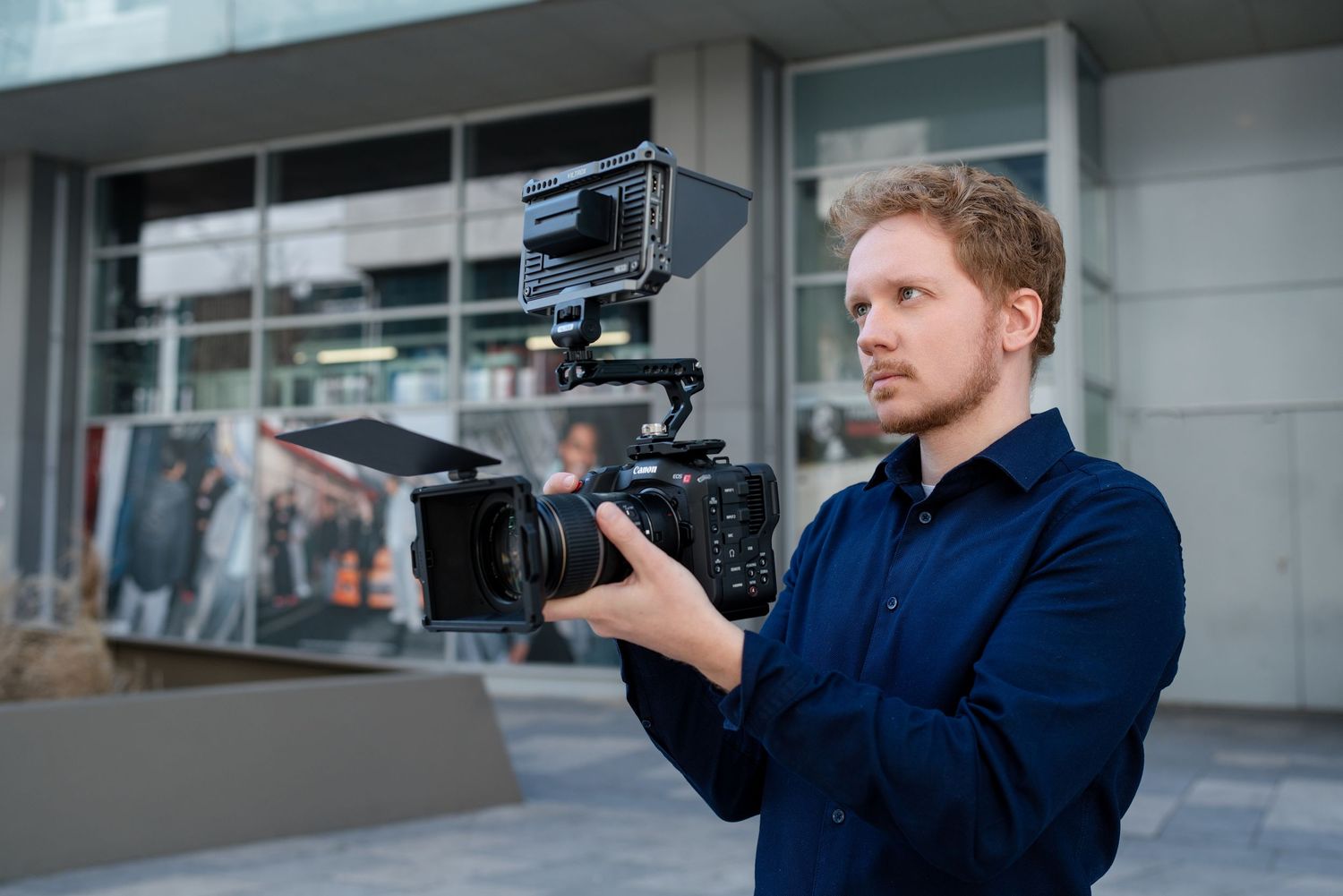 Professional videographer filming with a handheld camera setup while moving through an office building.