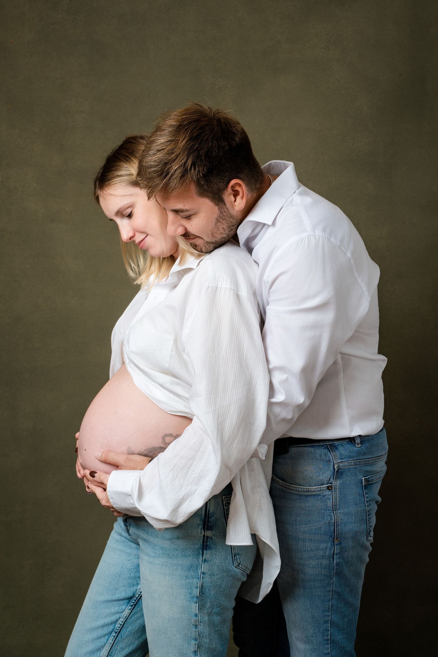 Tender family moments captured in white shirts and blue jeans during studio photography session.