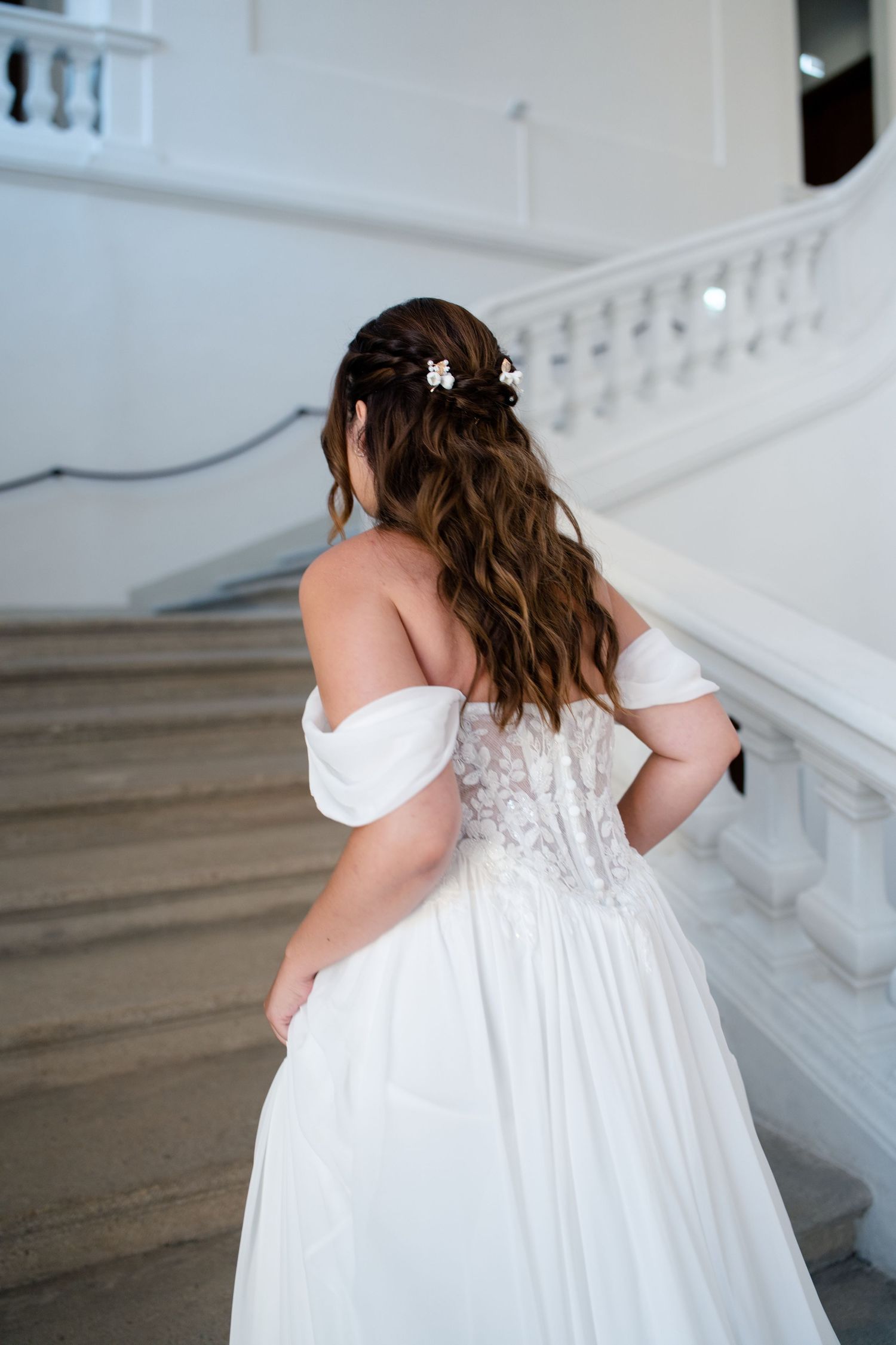 Back view of wedding dress showing intricate lace detail and off-shoulder design.