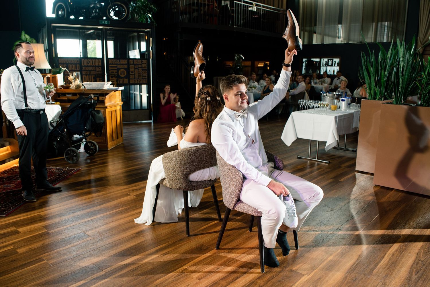 Wedding party dancing and celebrating on a wooden dance floor at an indoor venue.