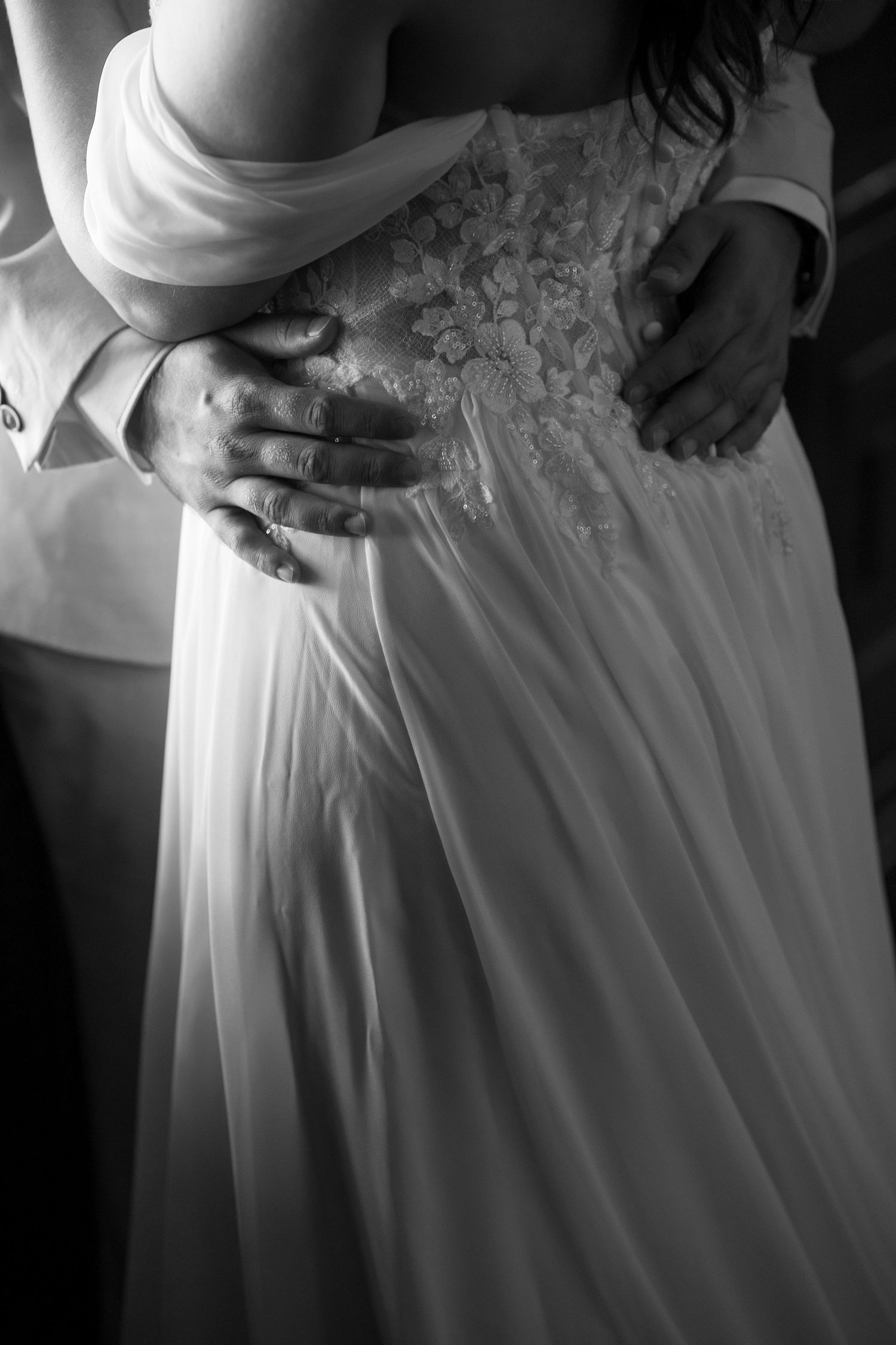 Black and white close-up details of a wedding dress with intricate lace bodice.