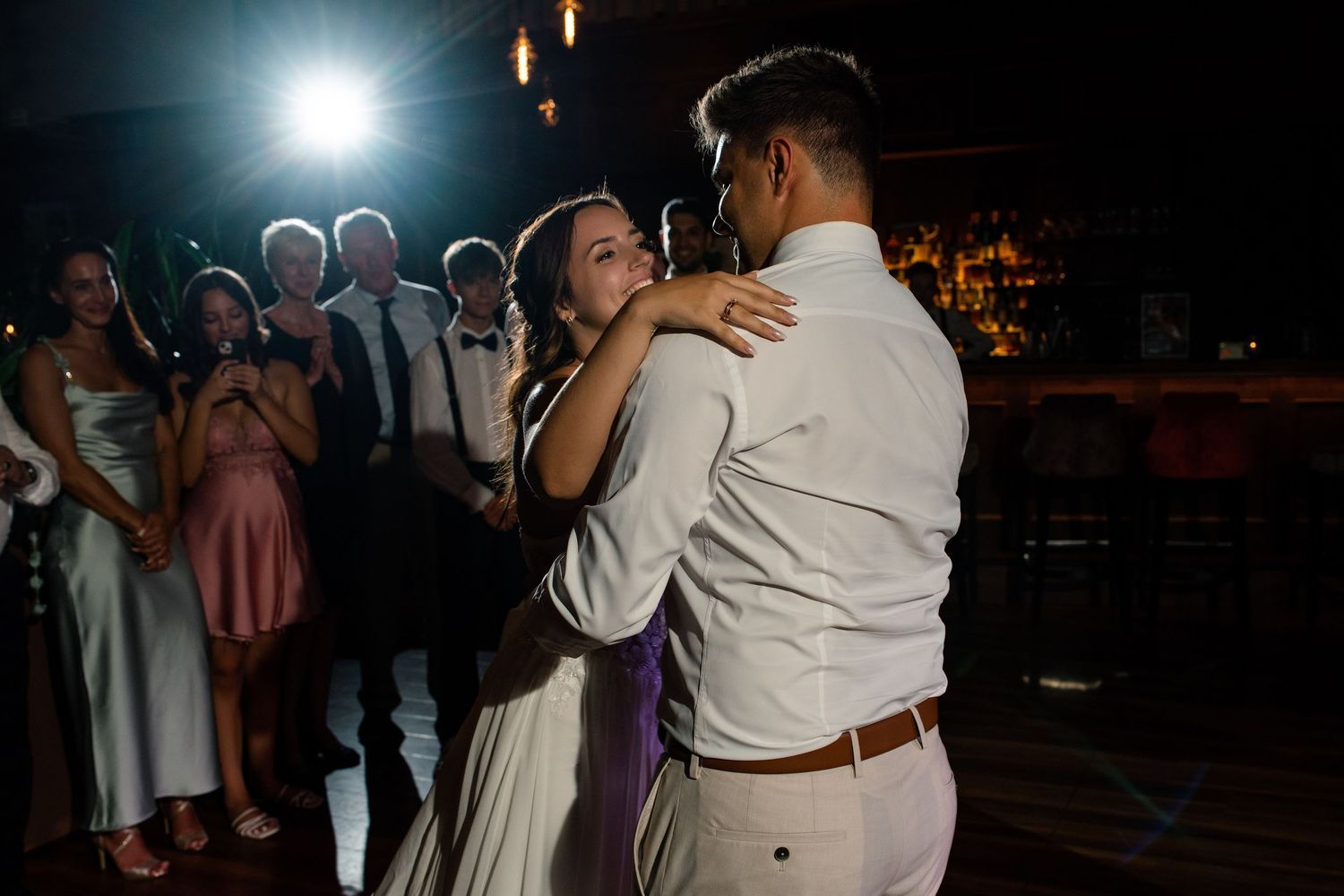 Romantic first dance moment captured at wedding reception with dramatic lighting.