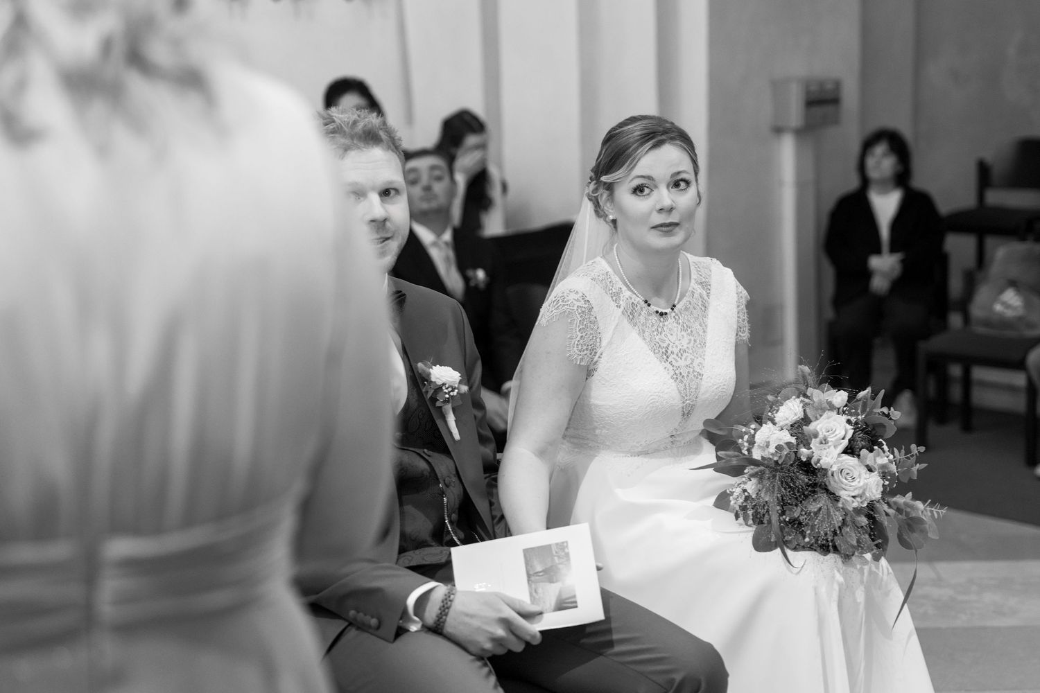 Wedding party members sharing emotional moments during a formal ceremony in black and white.