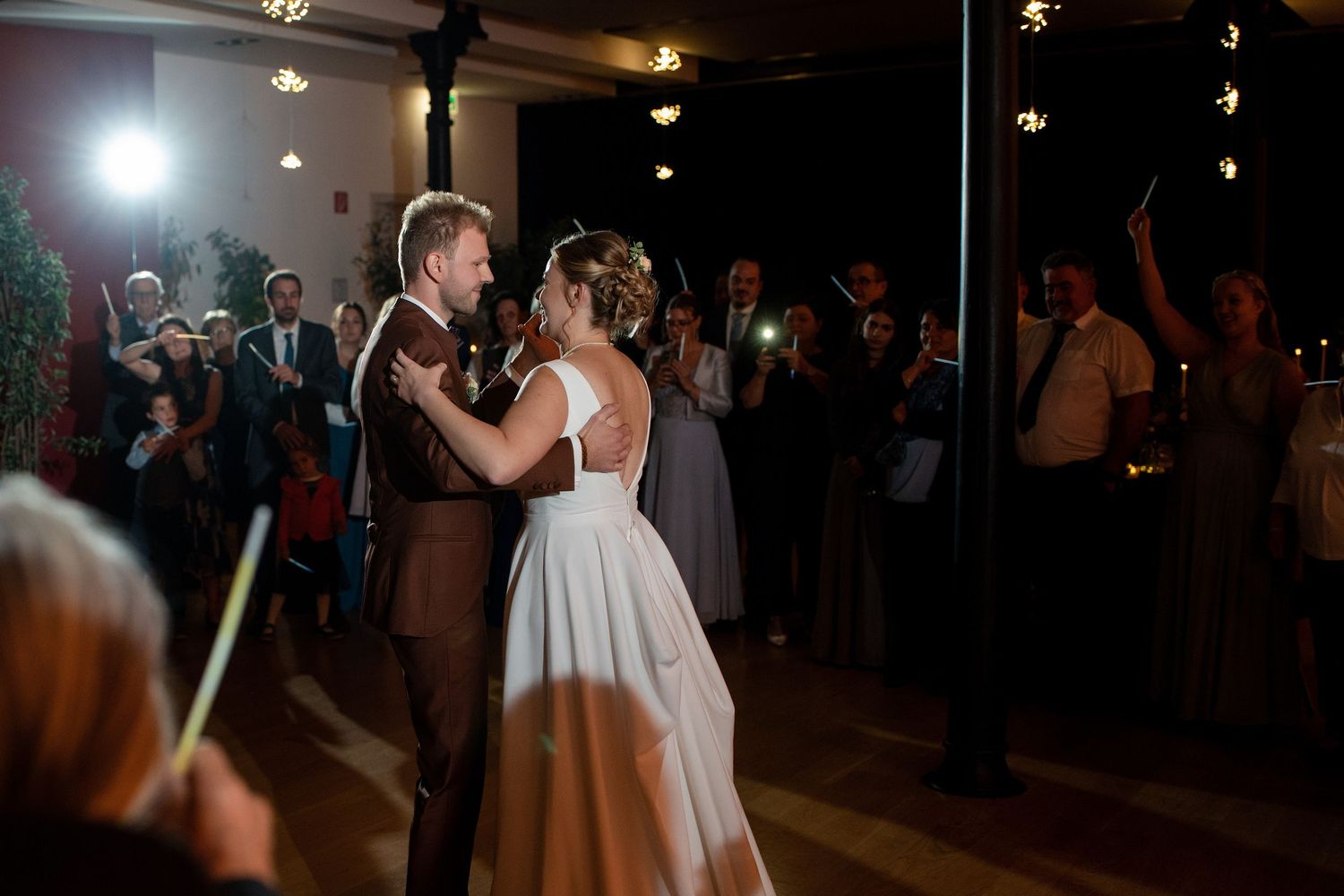 Couple sharing their first dance at wedding reception with dramatic lighting.