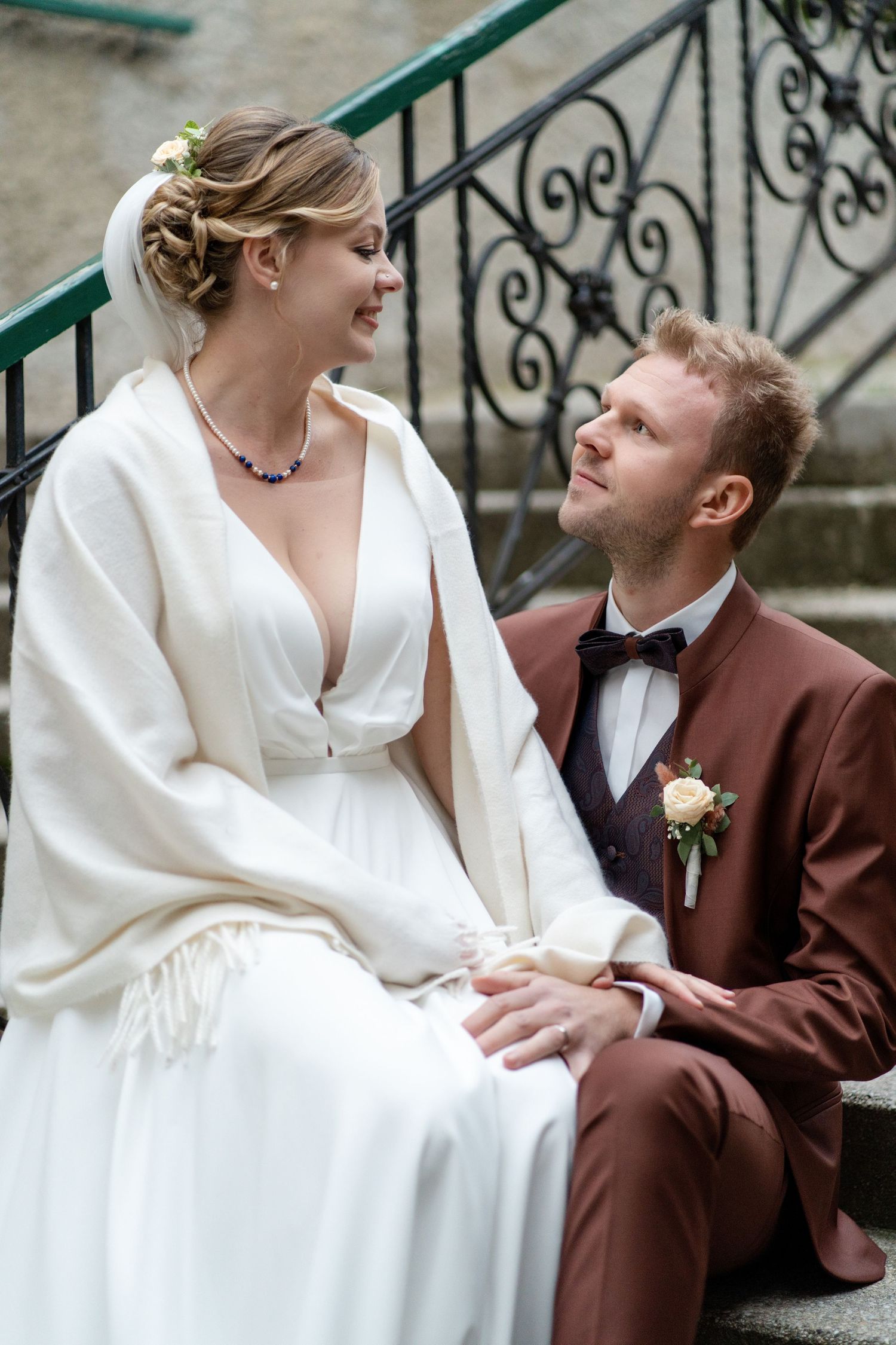 Romantic wedding portraits featuring the bride in white and groom in brown suit on ornate staircase.