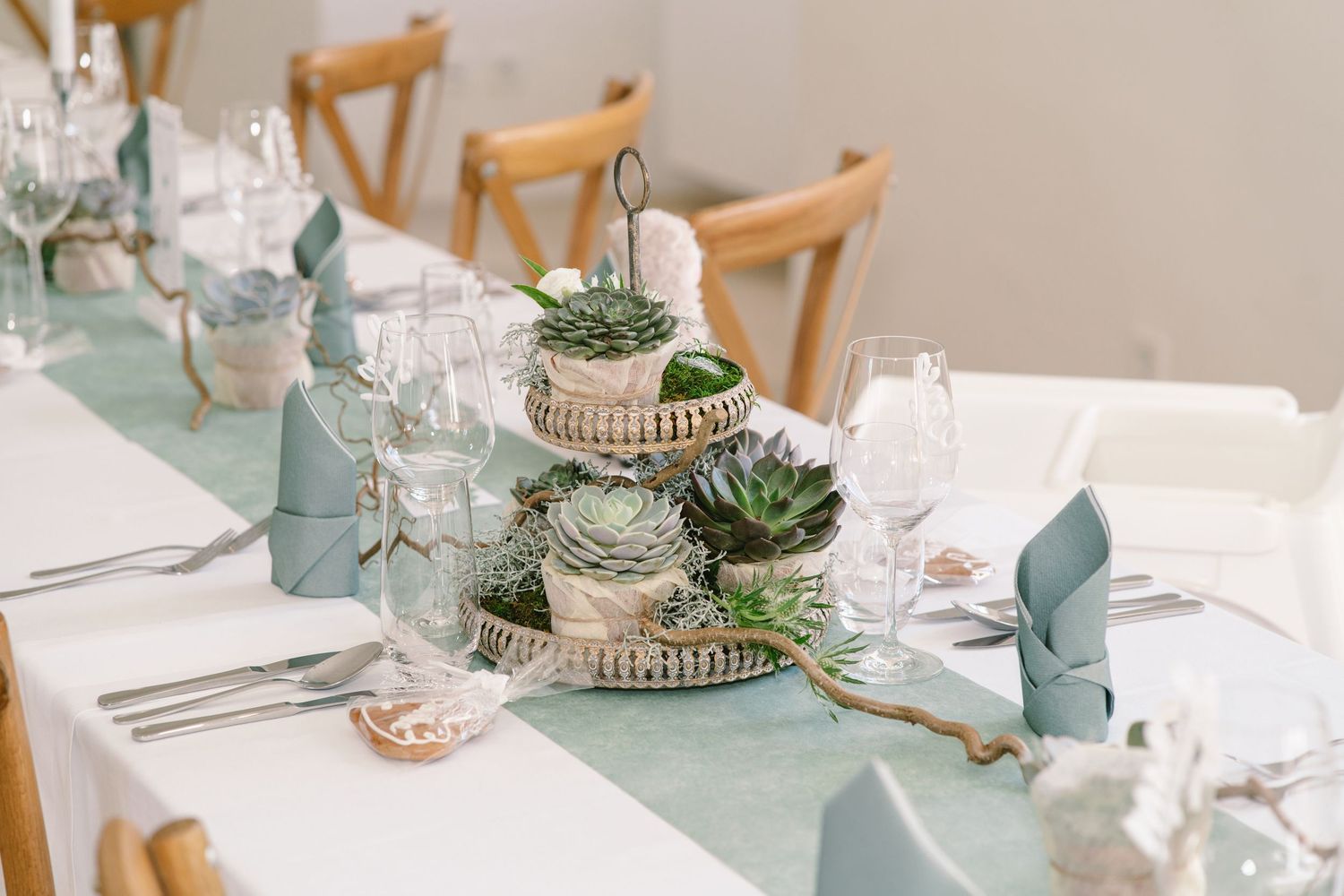 Wedding reception tables decorated with sage green runners and succulent centerpieces.