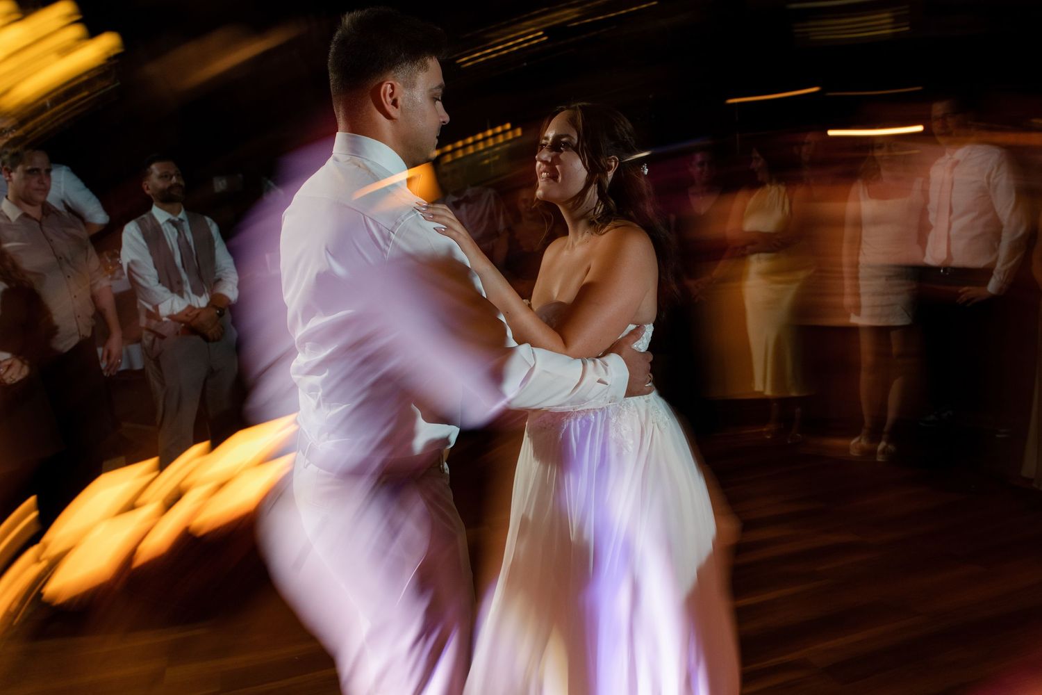 Dynamic dance floor moments captured with motion blur at wedding reception.