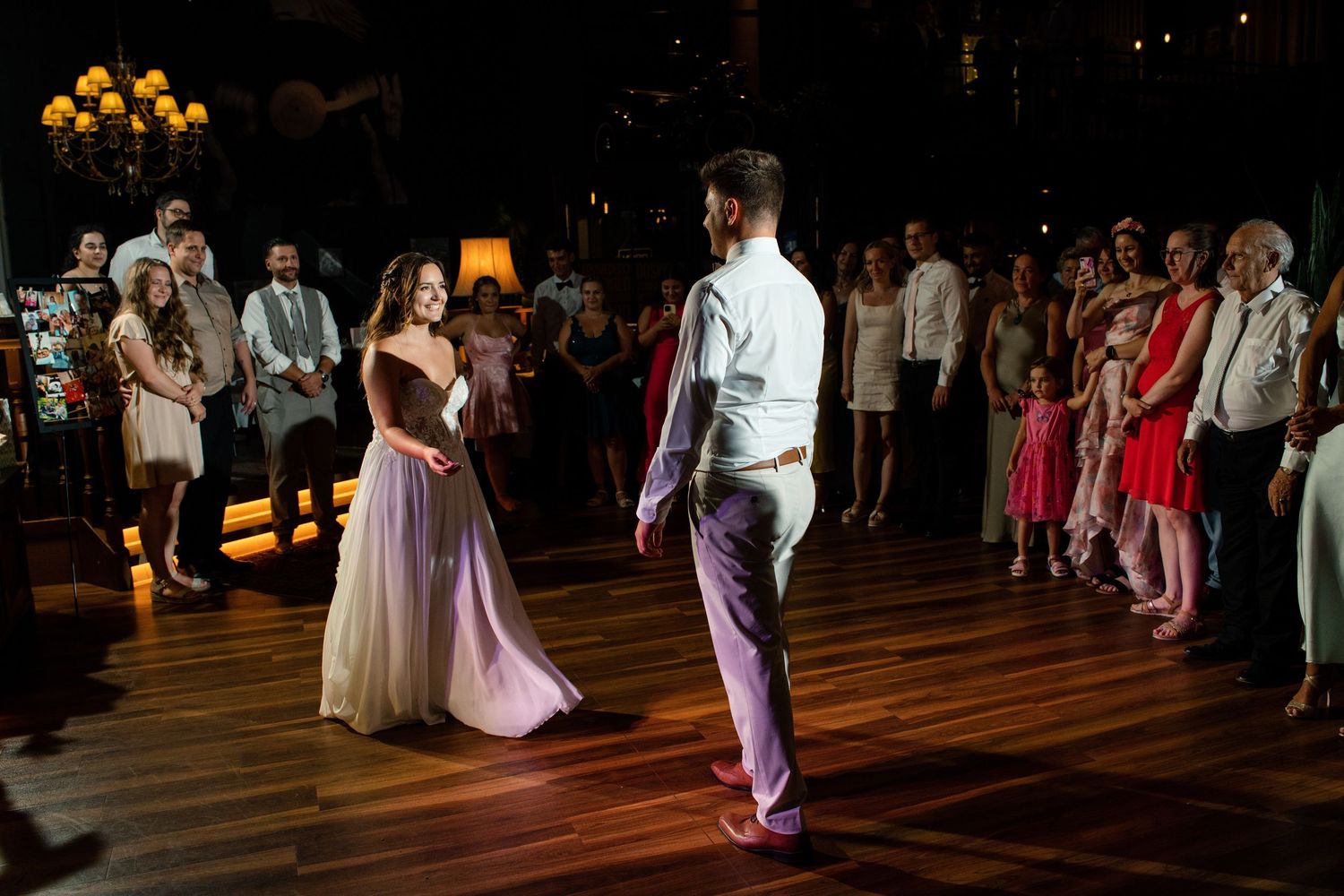 Couples slow dancing at an elegant wedding reception with ambient lighting.