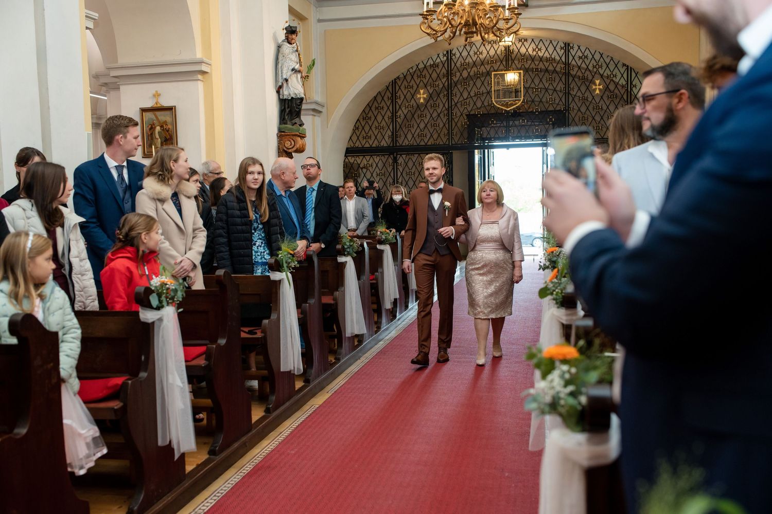 Wedding guests dance and celebrate on an elegant ballroom floor under a crystal chandelier.