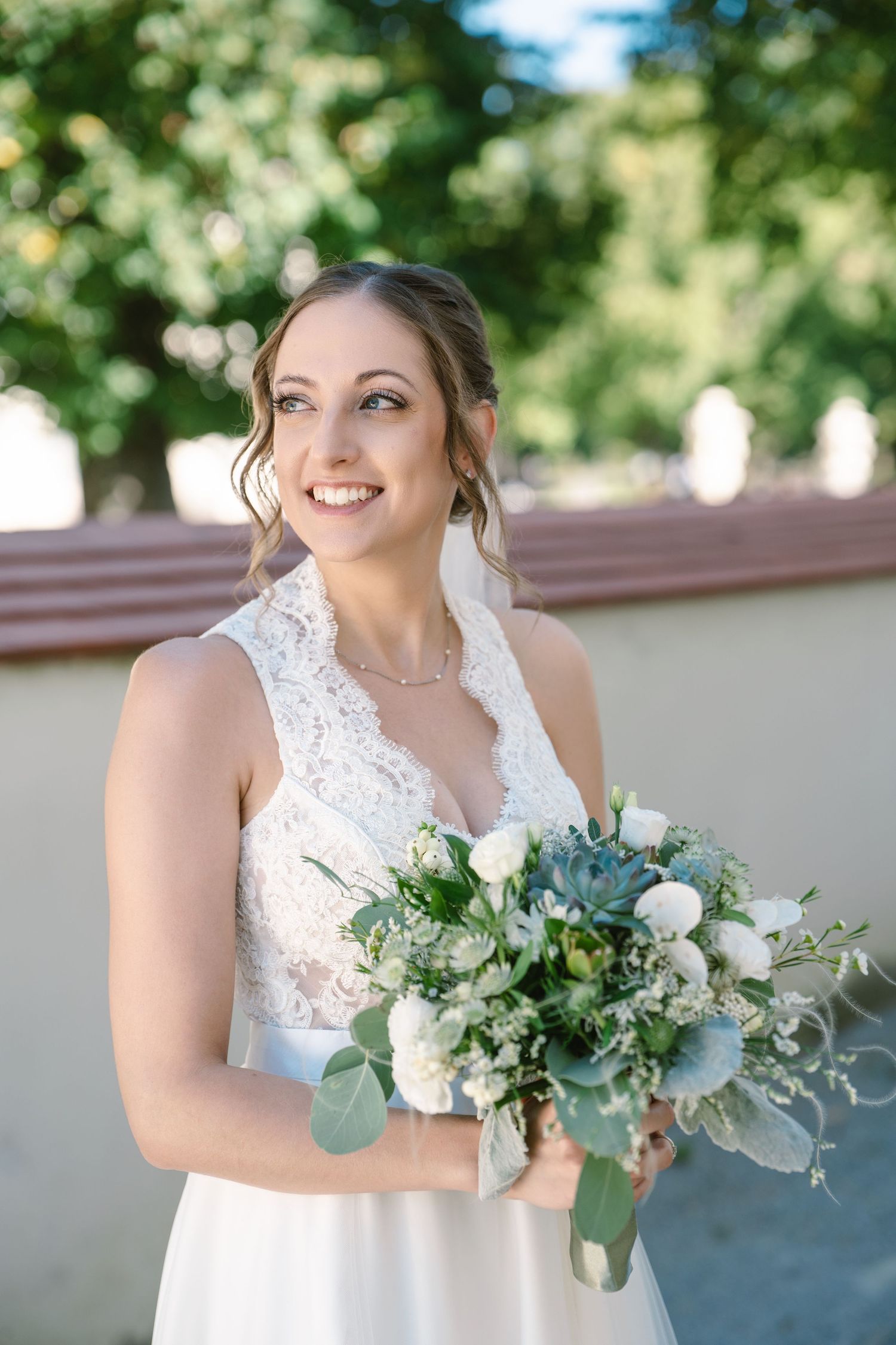Bridal bouquet featuring white flowers and eucalyptus leaves against light background.