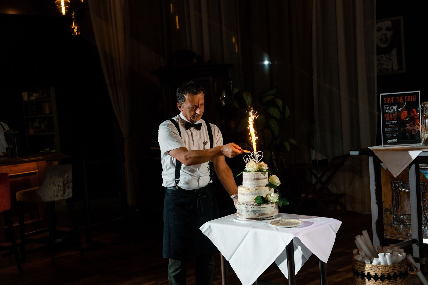 Sparklers illuminate a dark reception venue as guests gather around.