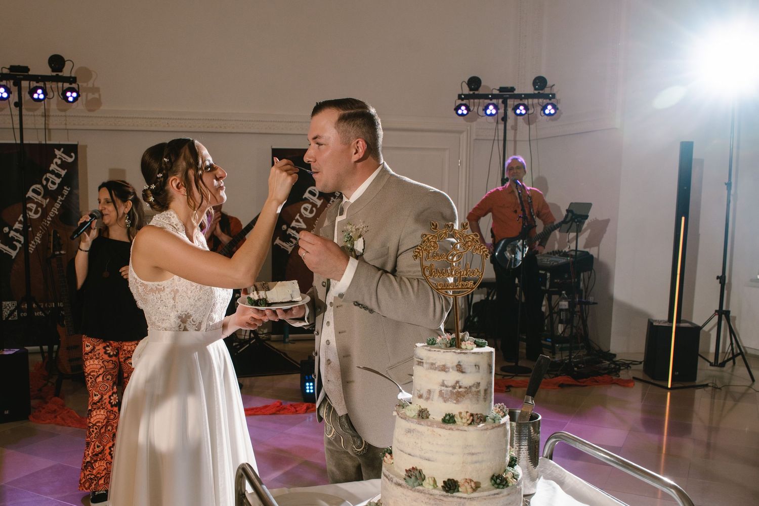 Newlyweds share a sweet moment while cutting their traditional tiered wedding cake.
