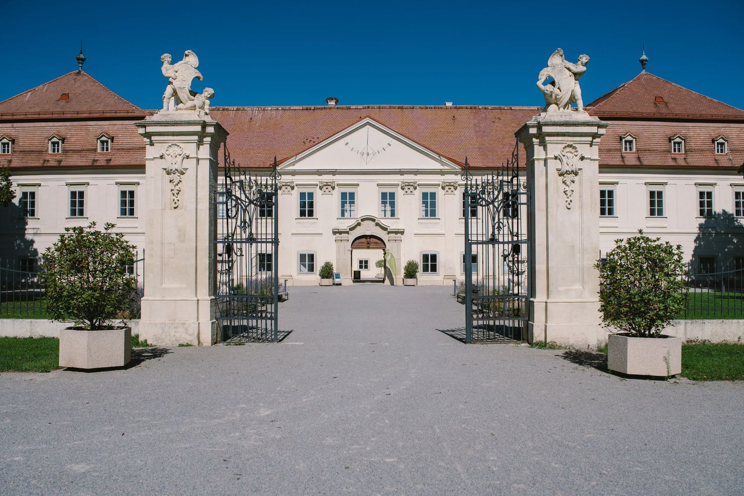 Symmetrical view of classical mansion architecture with stone pillars and statues.
