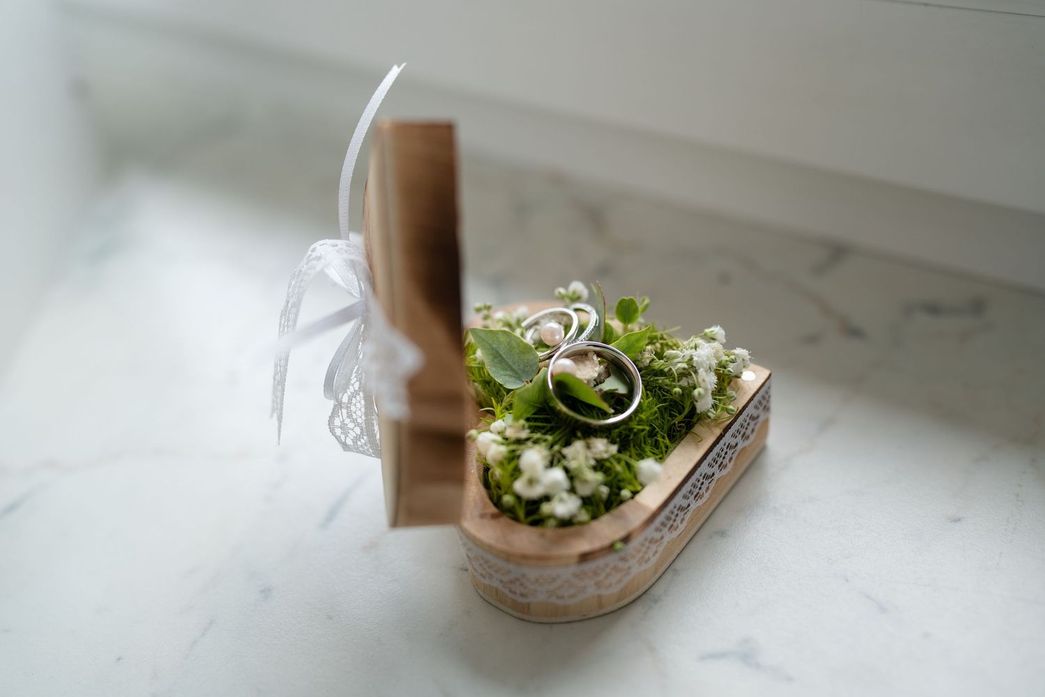 Elegant floral arrangements in small glass vases sit on a white marble surface near a window.