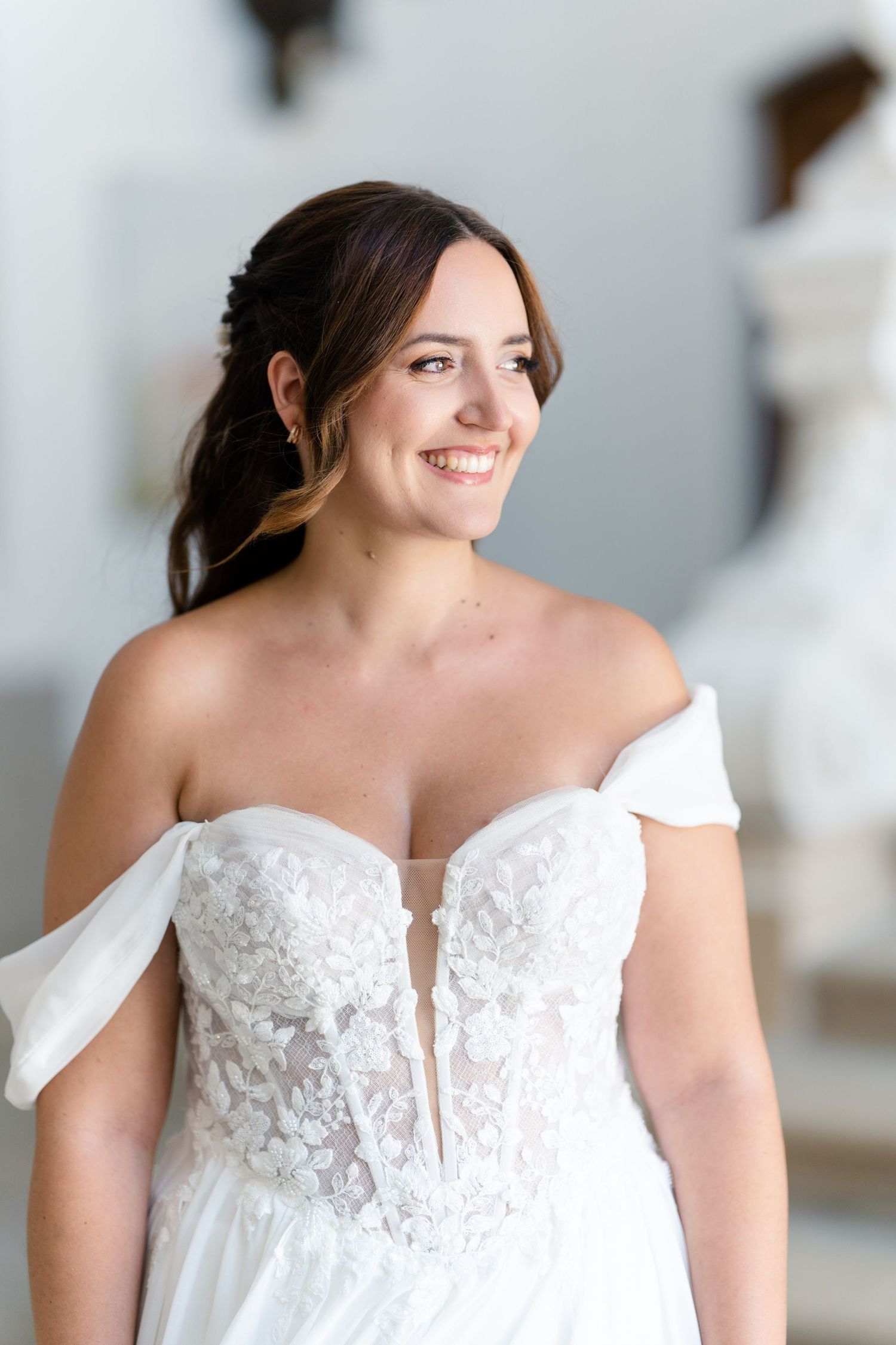 Bride wearing off-shoulder white wedding gown with lace detailing.