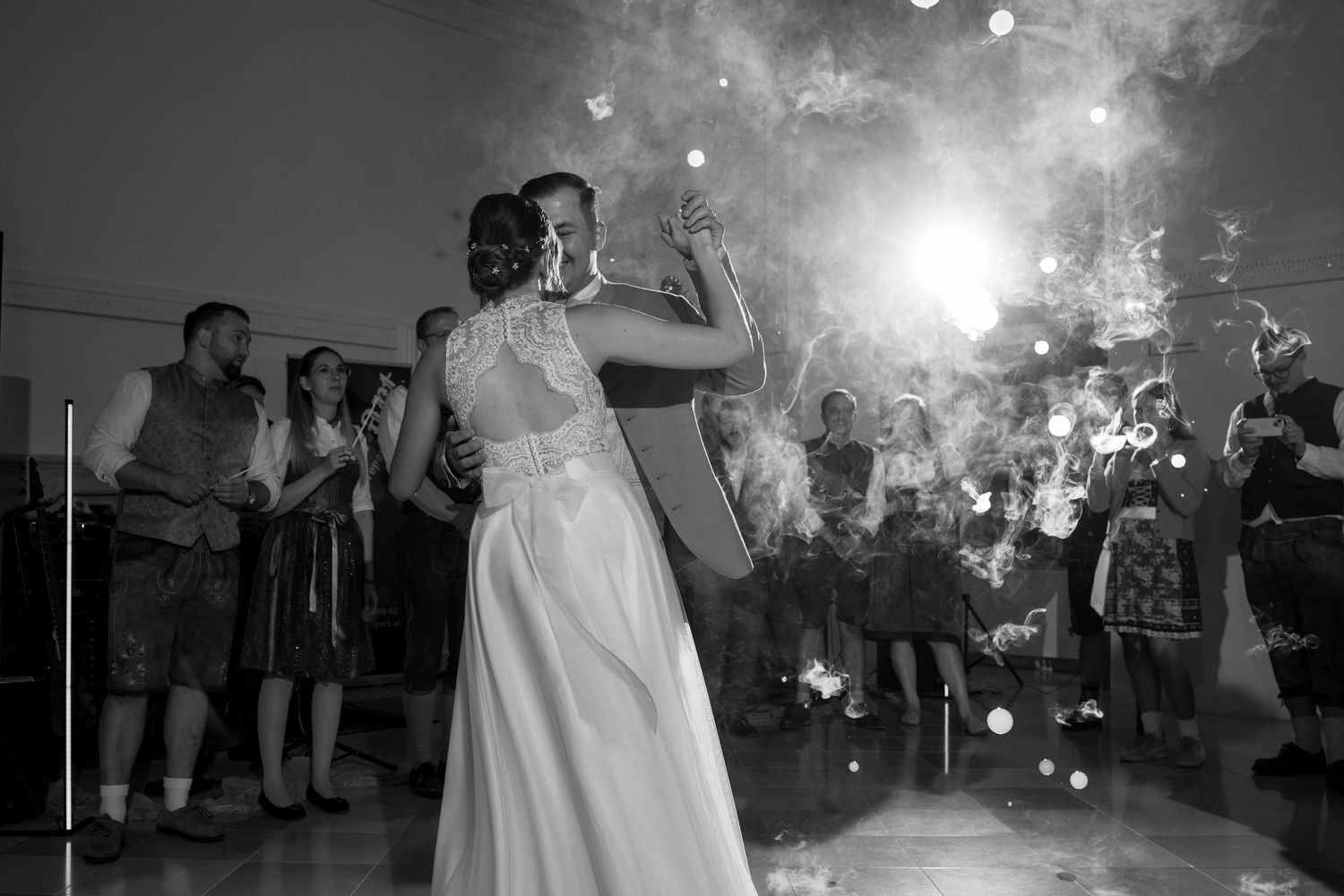 Newlyweds dance together under dramatic lighting and sparkler effects at their reception celebration.
