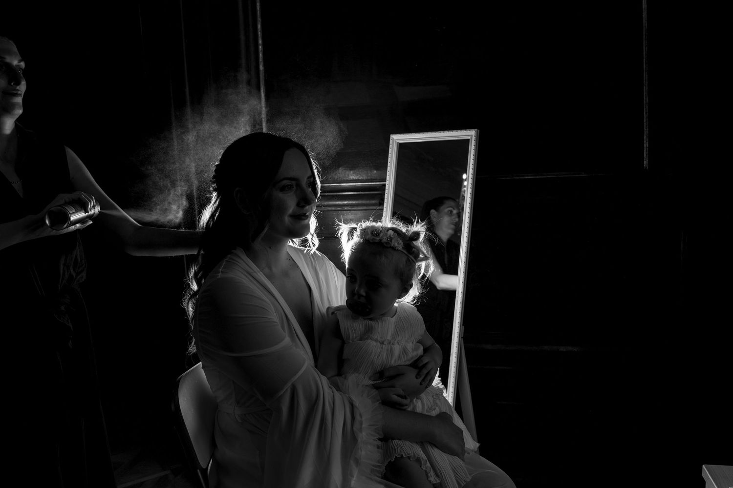 Black and white image of styling session with mirror reflection in dark room.