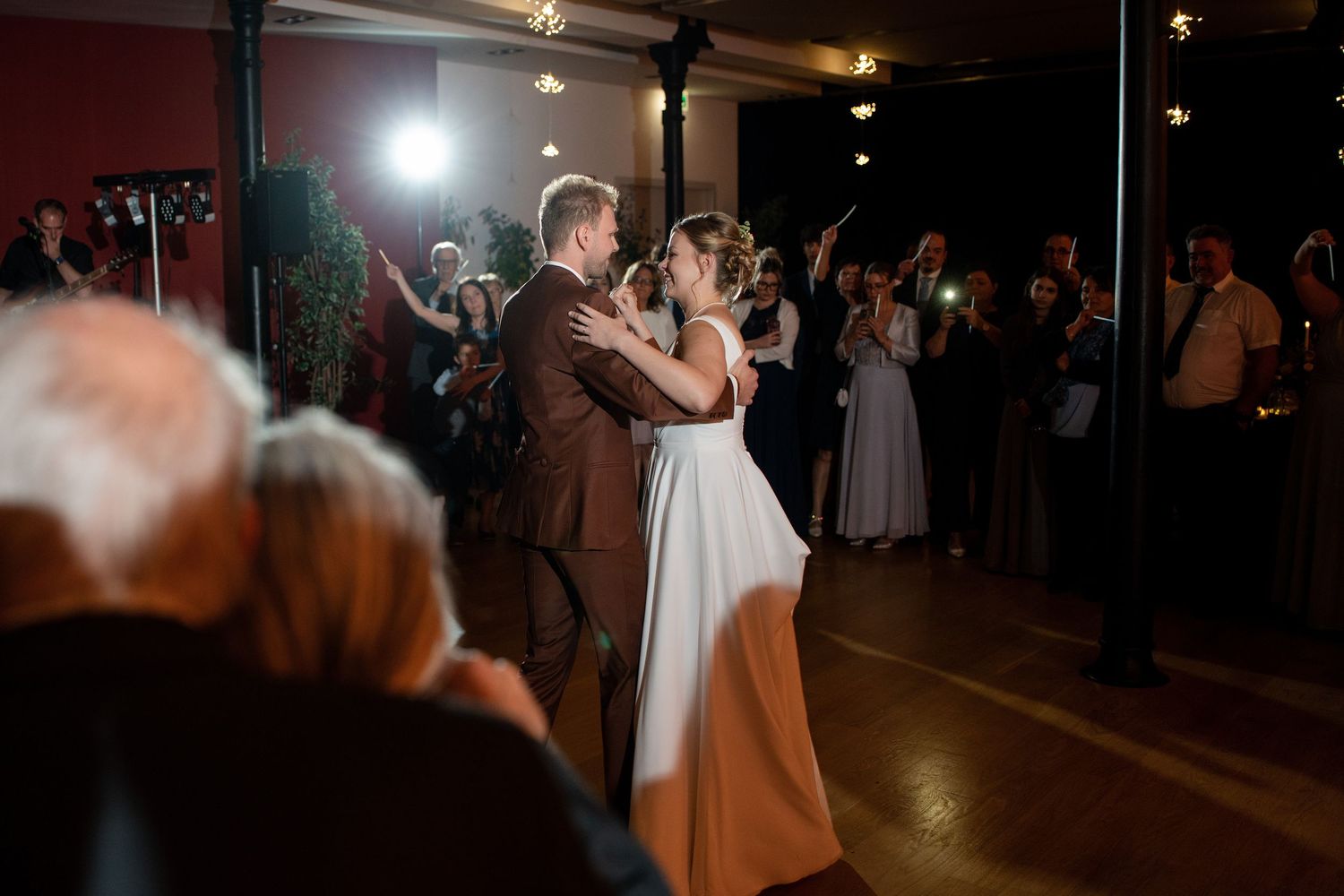 Dimly lit dance floor with wedding guests celebrating at night.