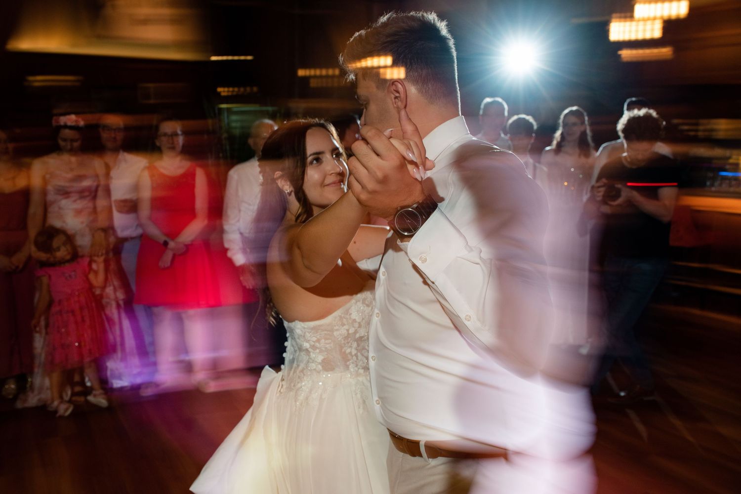 Wedding reception dance floor filled with couples in motion under dramatic lighting.
