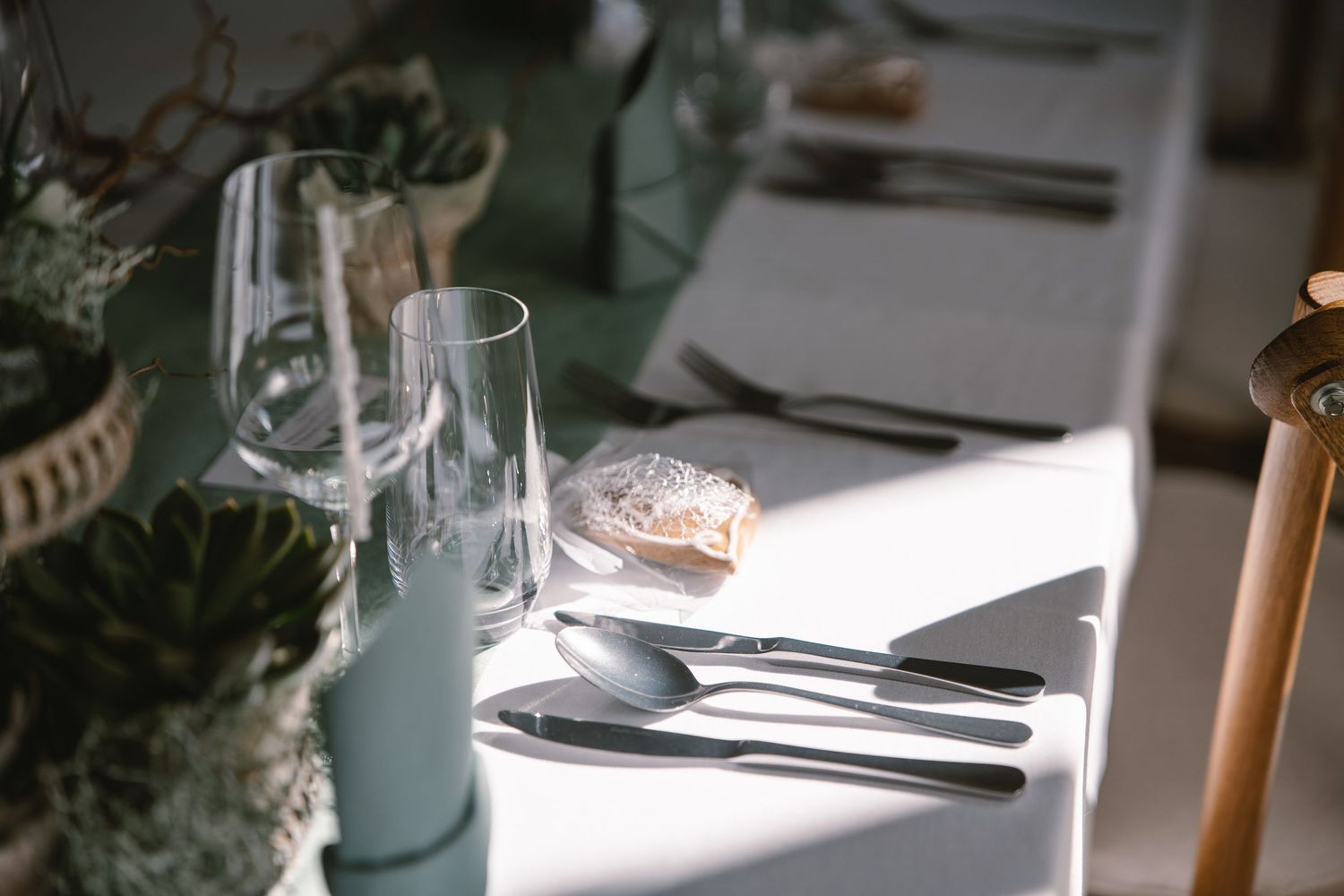 Modern table settings with succulents and glassware for wedding reception.