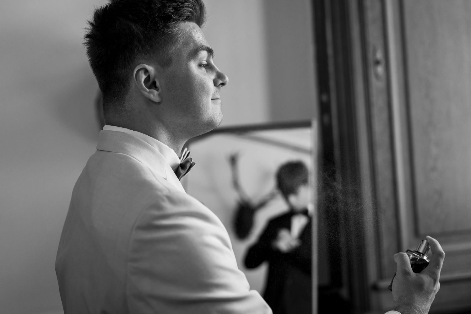 Black and white profile shot of person in formal attire looking out window.