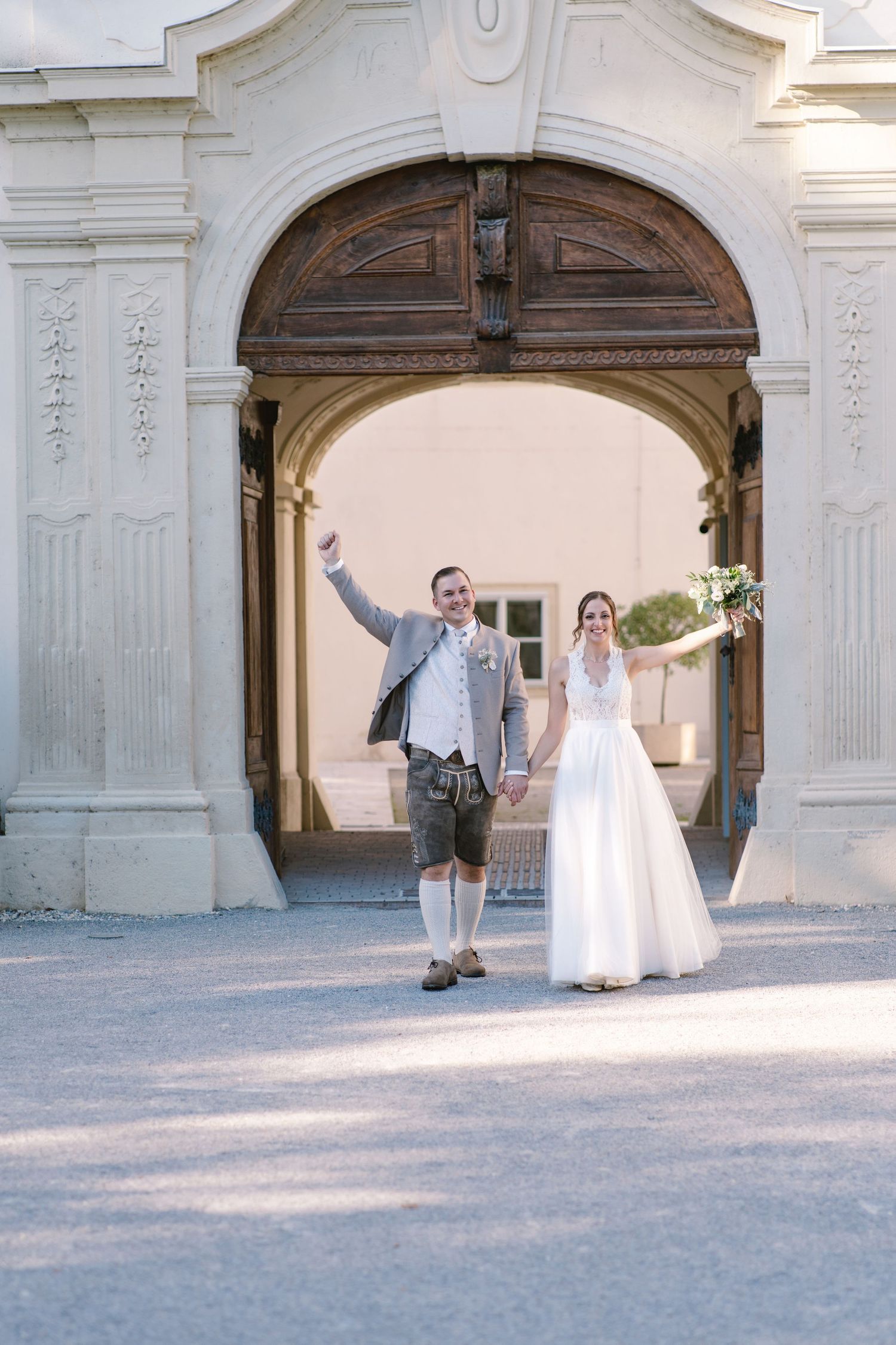 Wedding party walking through elegant stone archways at outdoor venue.