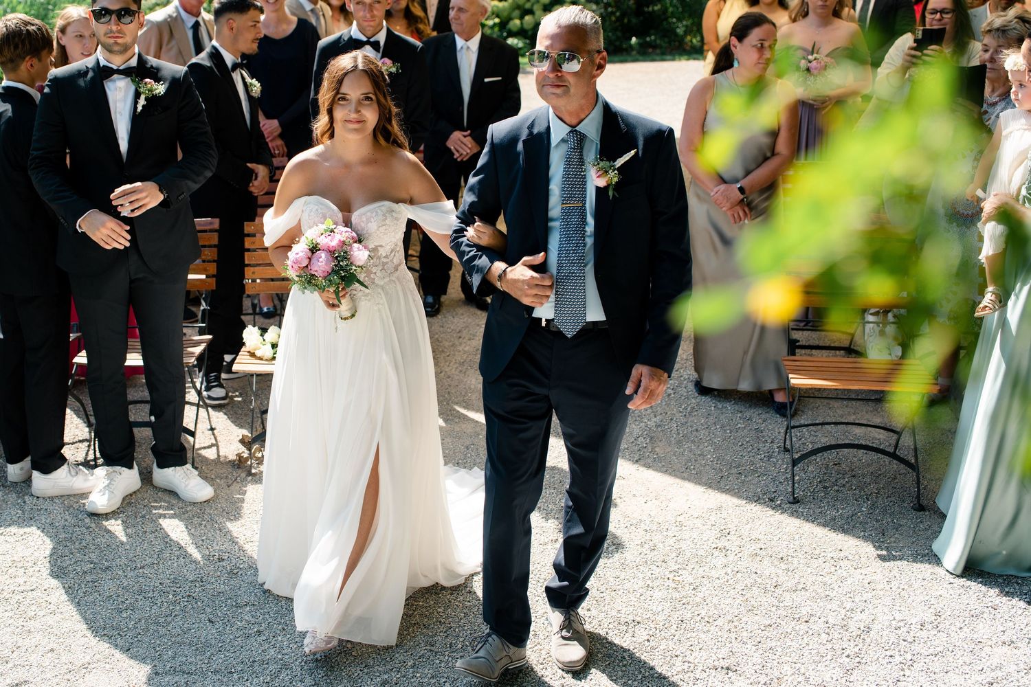Wedding celebration with guests walking on outdoor pathway.