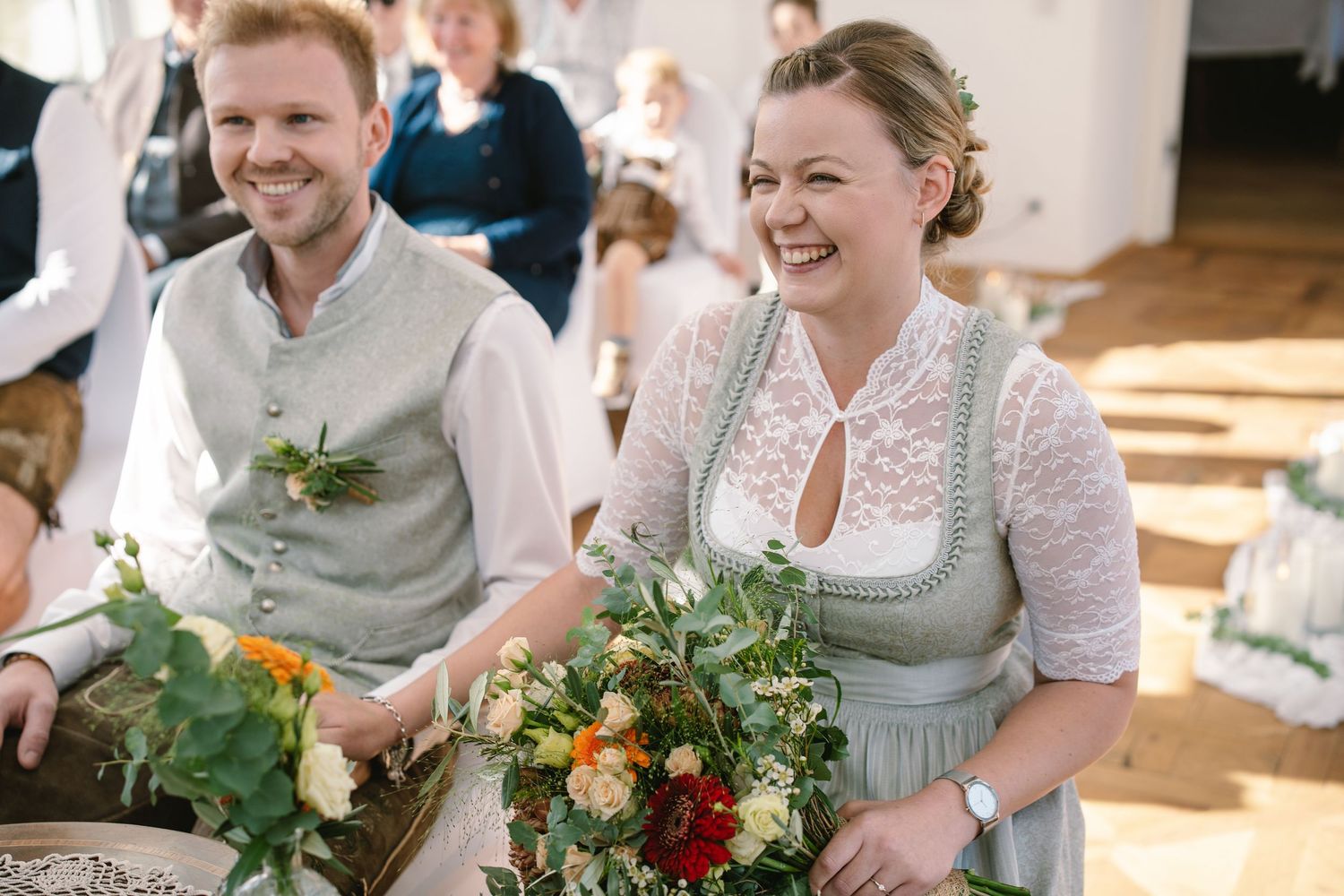 Wedding guests gather around tables decorated with floral centerpieces during a joyful celebration.