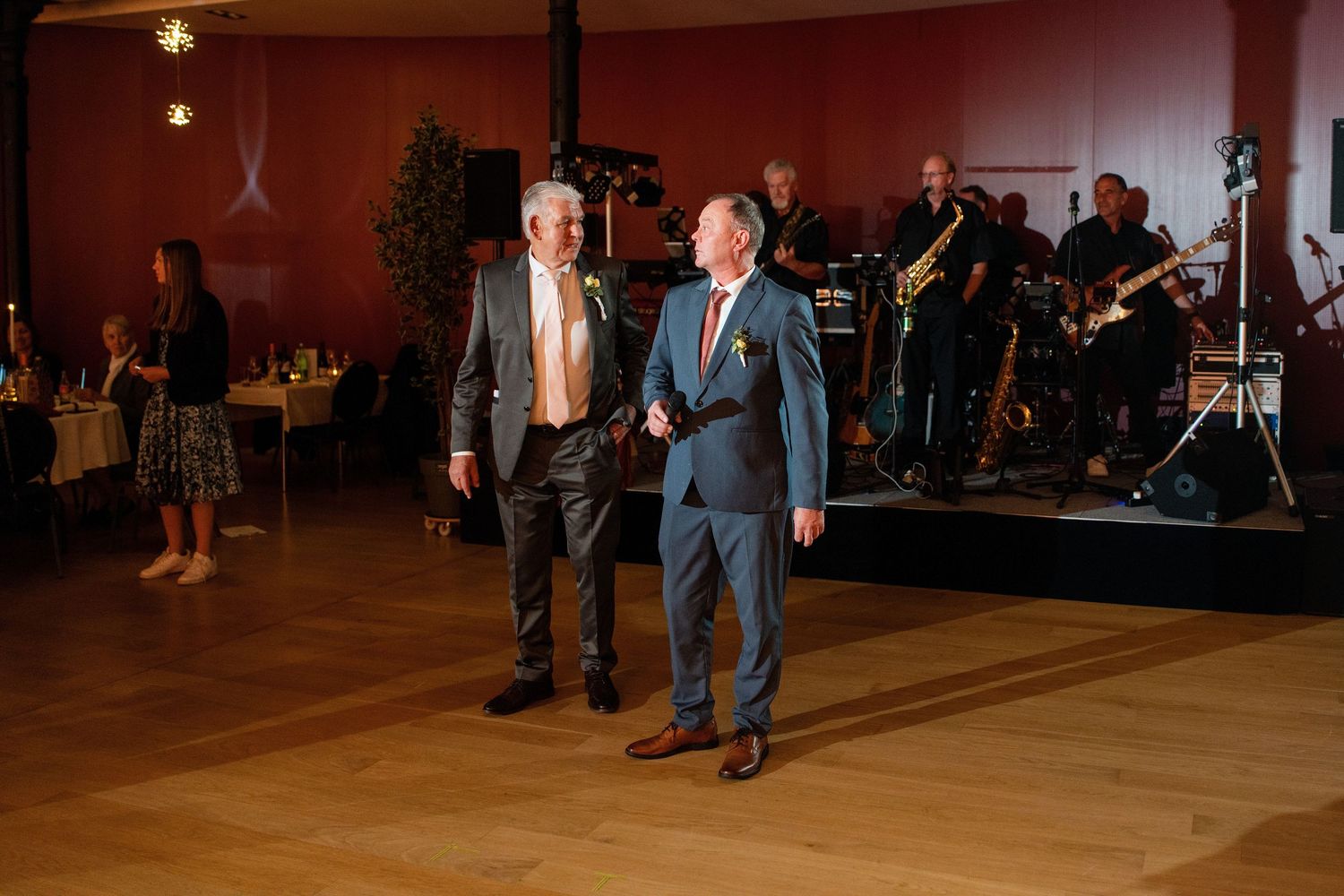 Wedding reception dance floor filled with celebrating guests in dimly lit venue.
