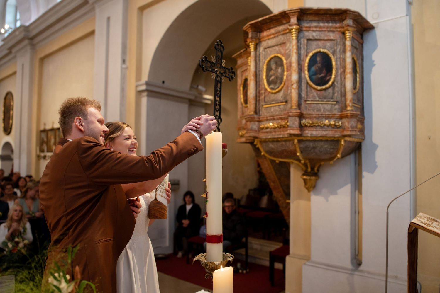 A person in a brown suit takes a photograph of an ornate wooden pulpit in a church interior.