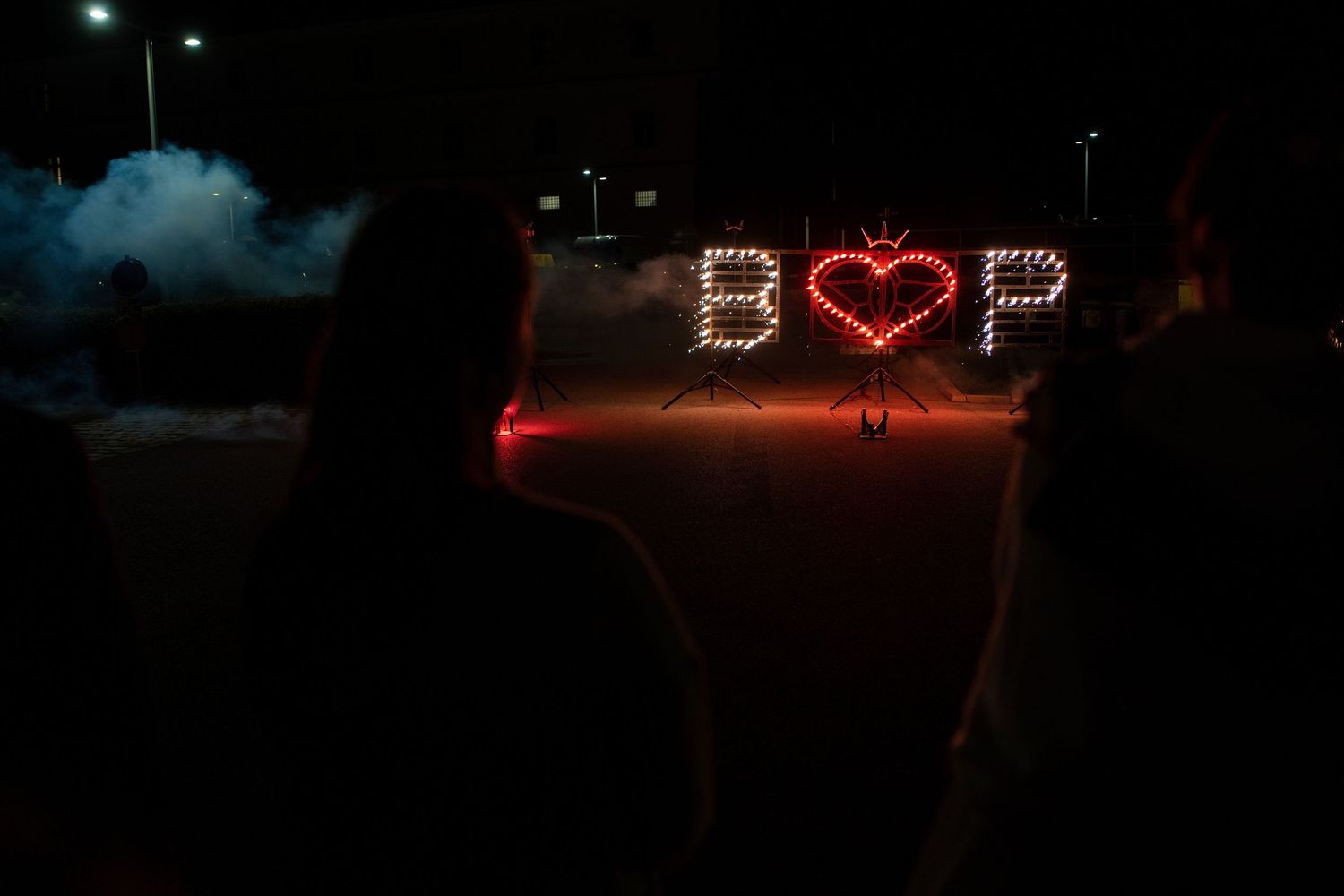 Illuminated heart sign glowing in red against a dark nighttime background.