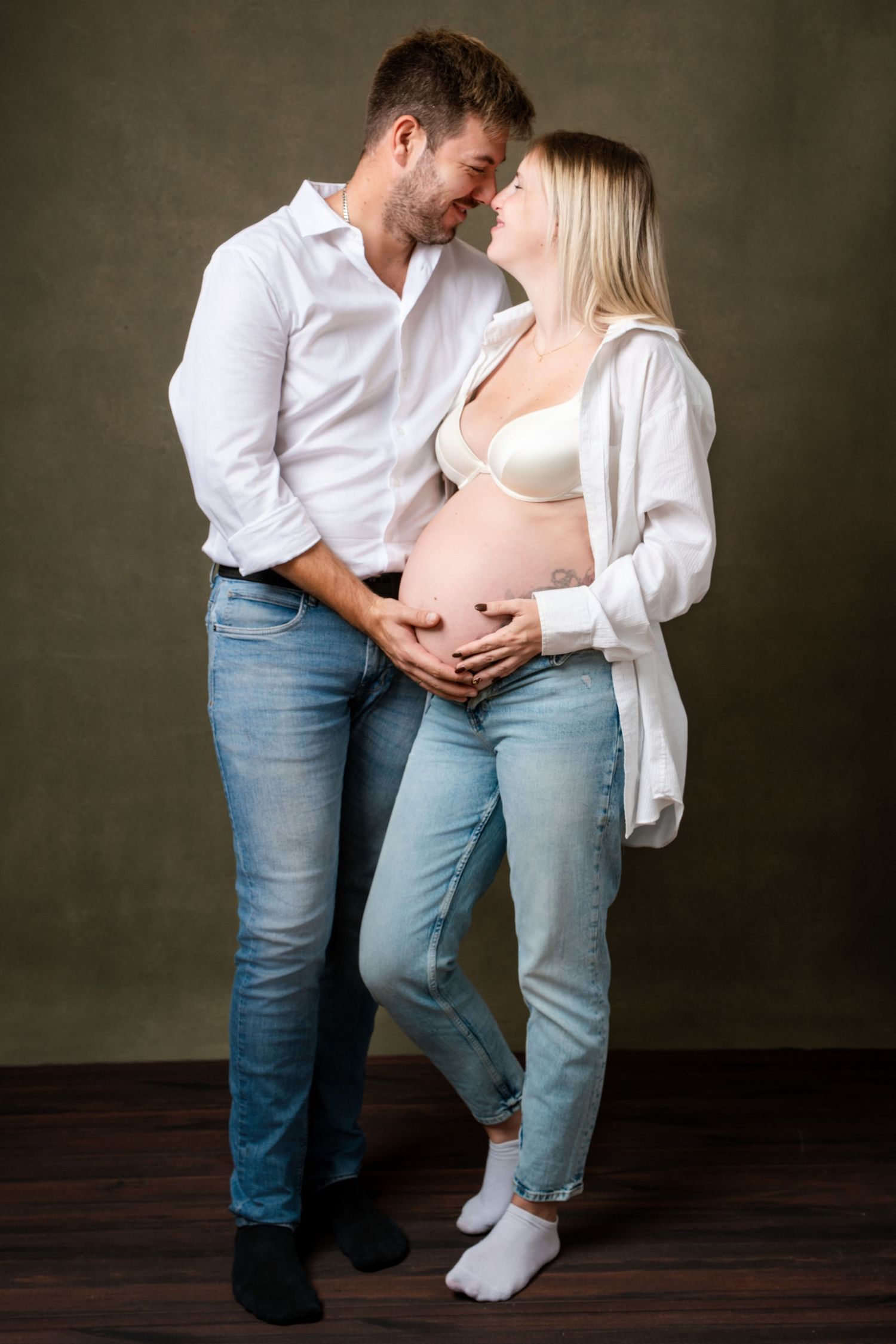 Studio portrait session showing intimate family moments in casual white and denim outfits.
