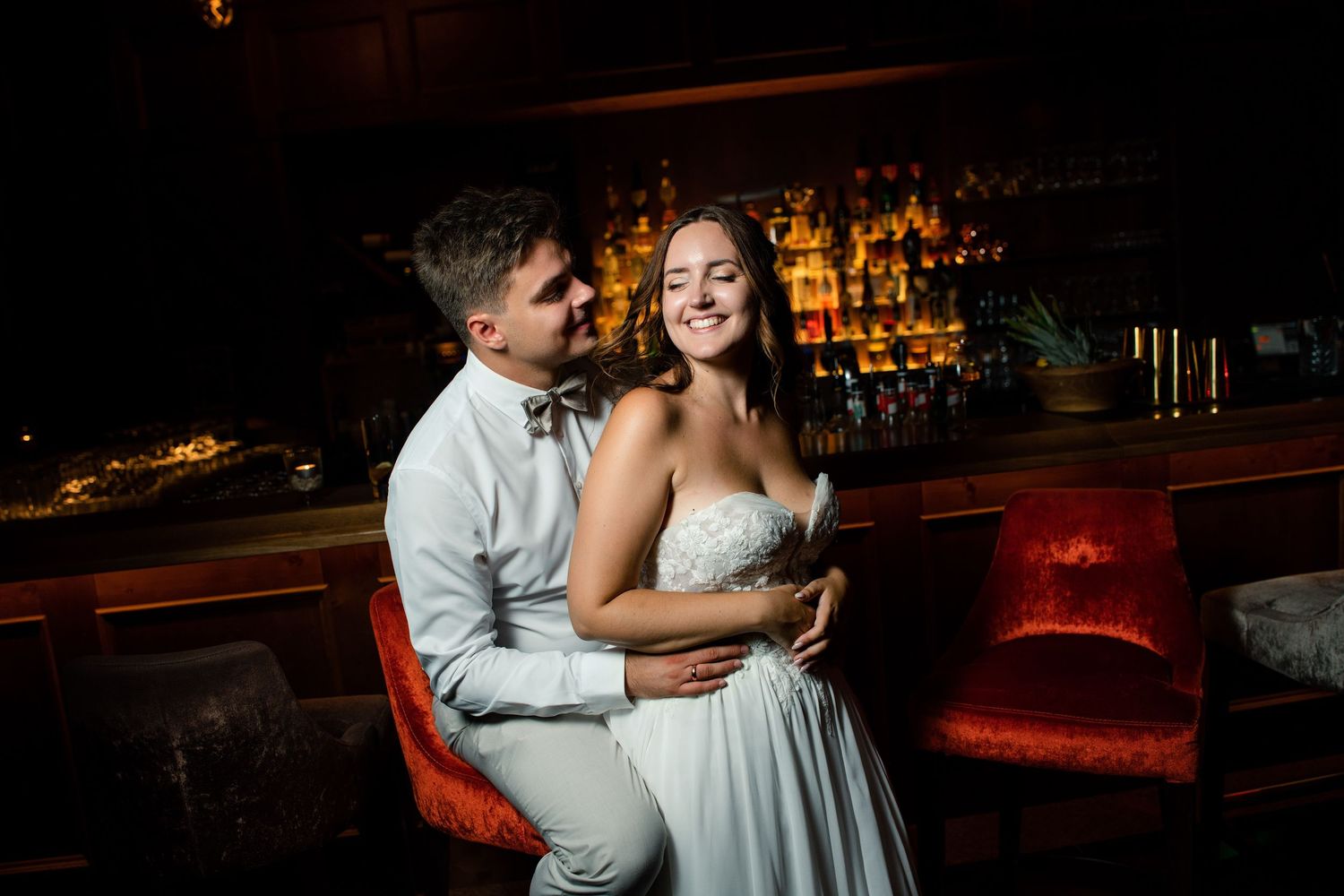 A romantic moment between newlyweds at a dimly lit bar setting.