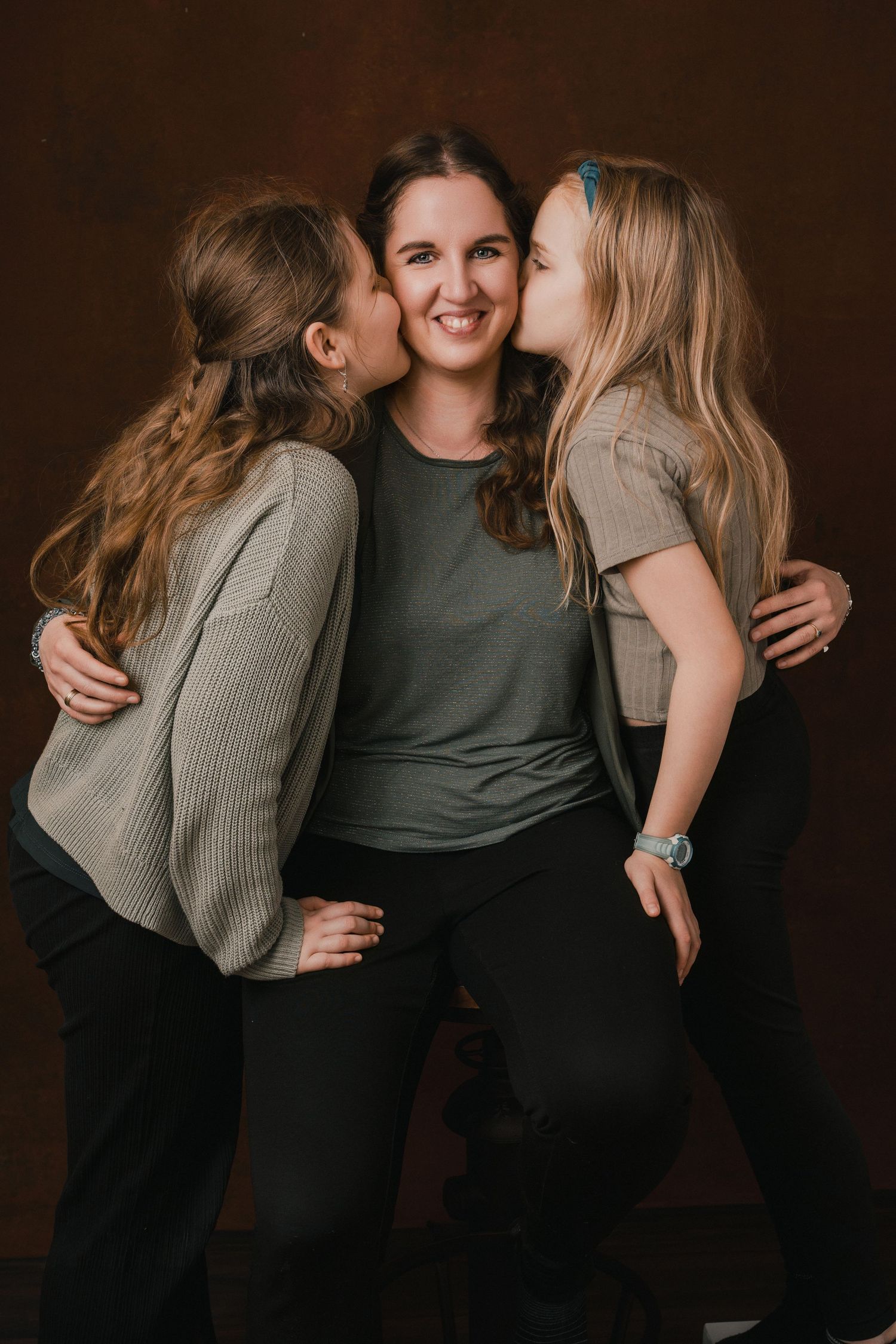 A series of candid photos showing three people embracing and laughing together against a dark brown backdrop.