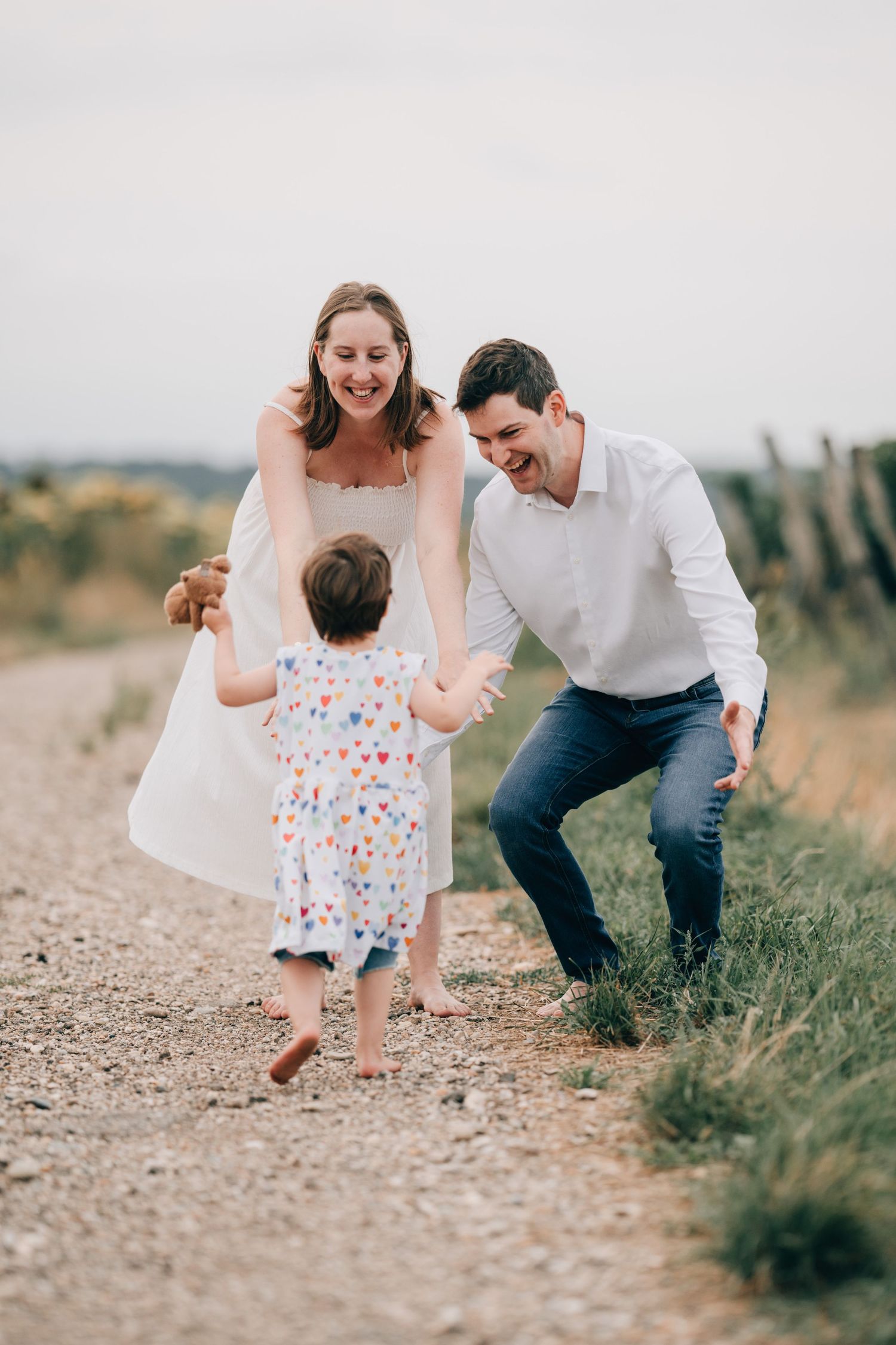 Family plays together on a grassy path during a candid outdoor photo session in warm natural lighting.