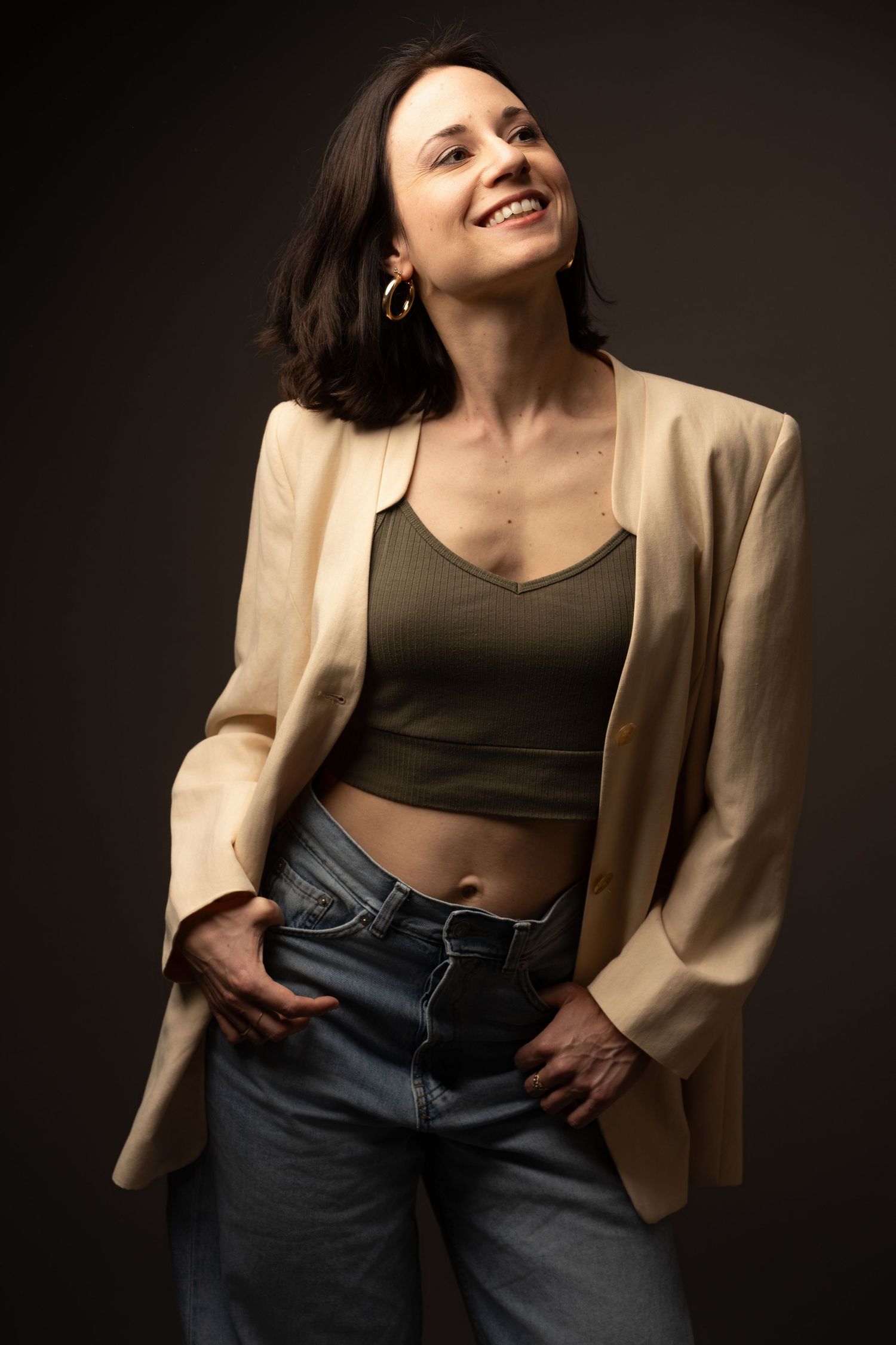 A fashion model wearing a beige blazer and black crop top poses against a dark background in a series of cropped shots.