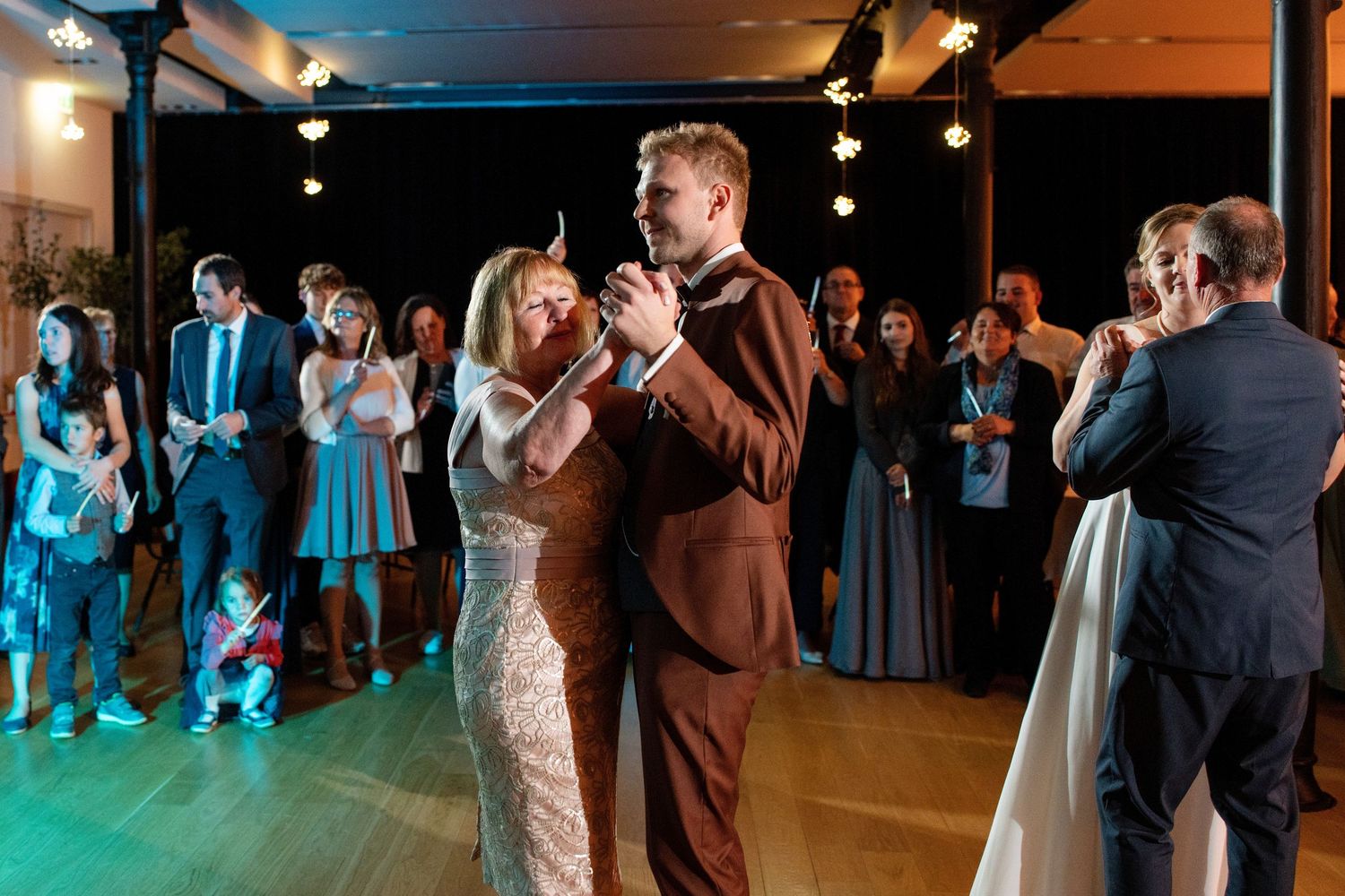 Newlyweds share their first dance under spotlights while guests watch from the sidelines.