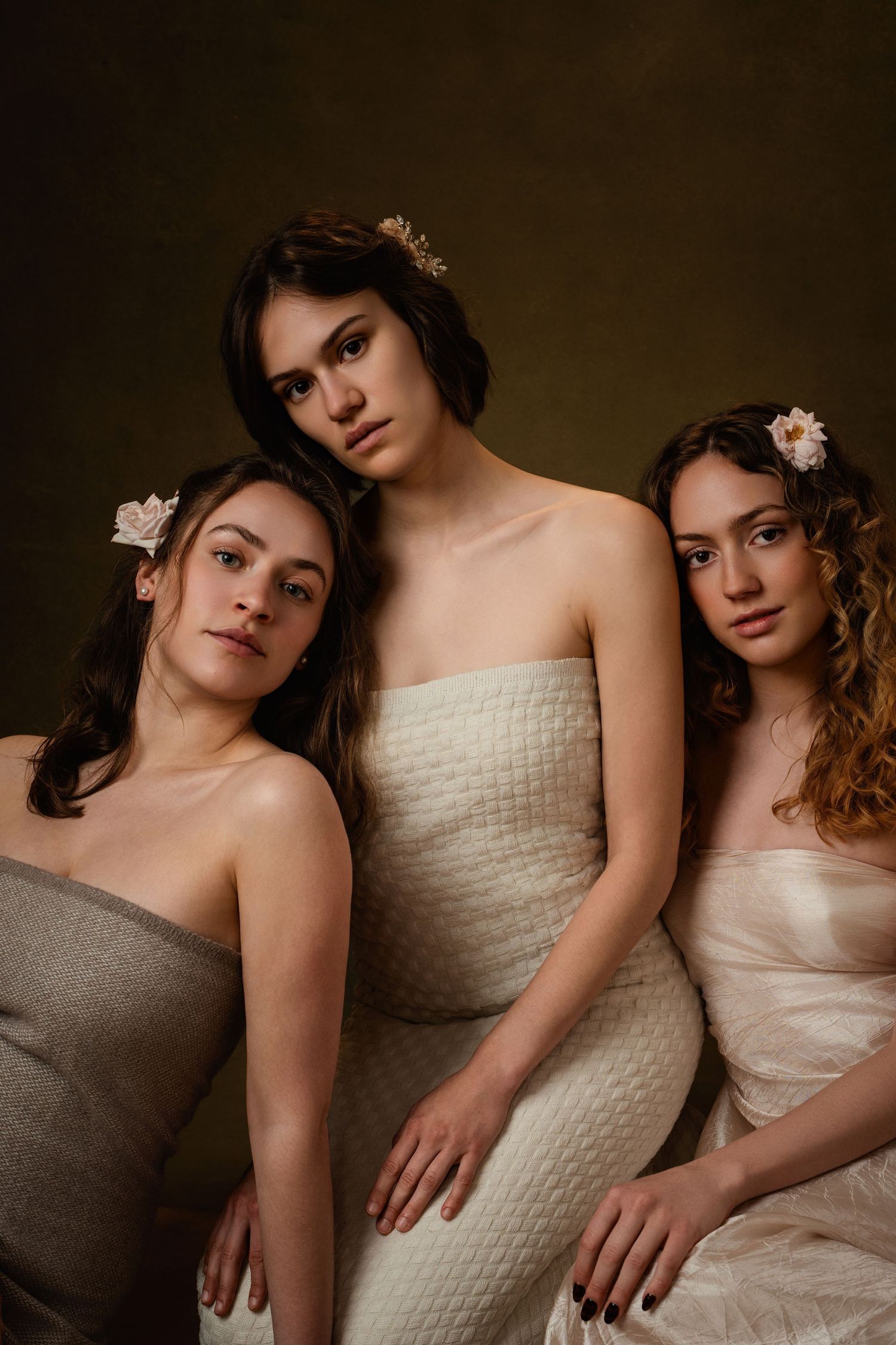 Fashion portrait series featuring models in white dresses posing together against dark brown background.