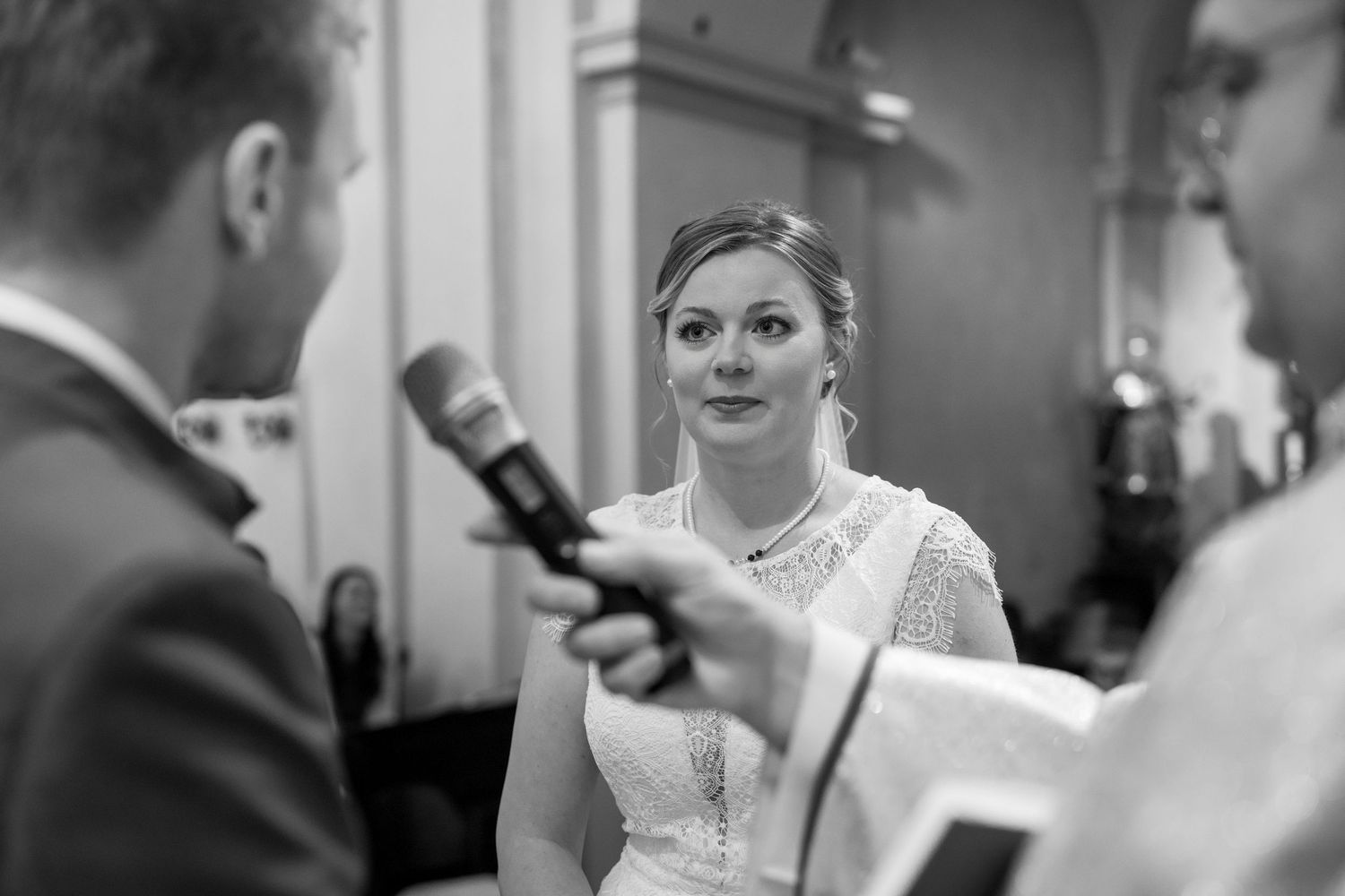 Wedding ceremony exchange of vows captured in black and white with microphones.