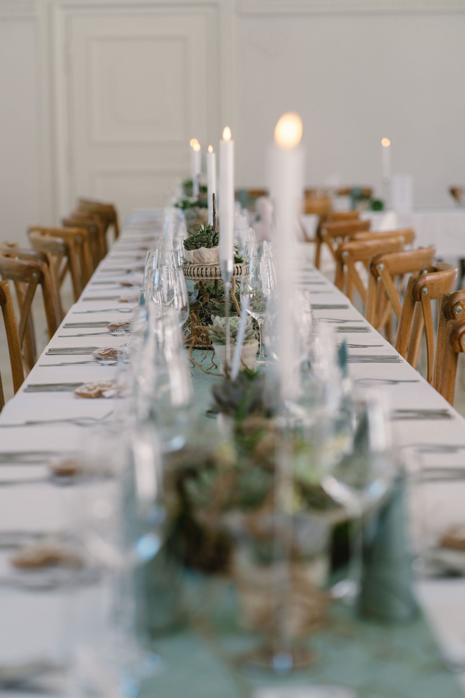 Long elegant wedding reception tables set with white linens and wooden chairs.
