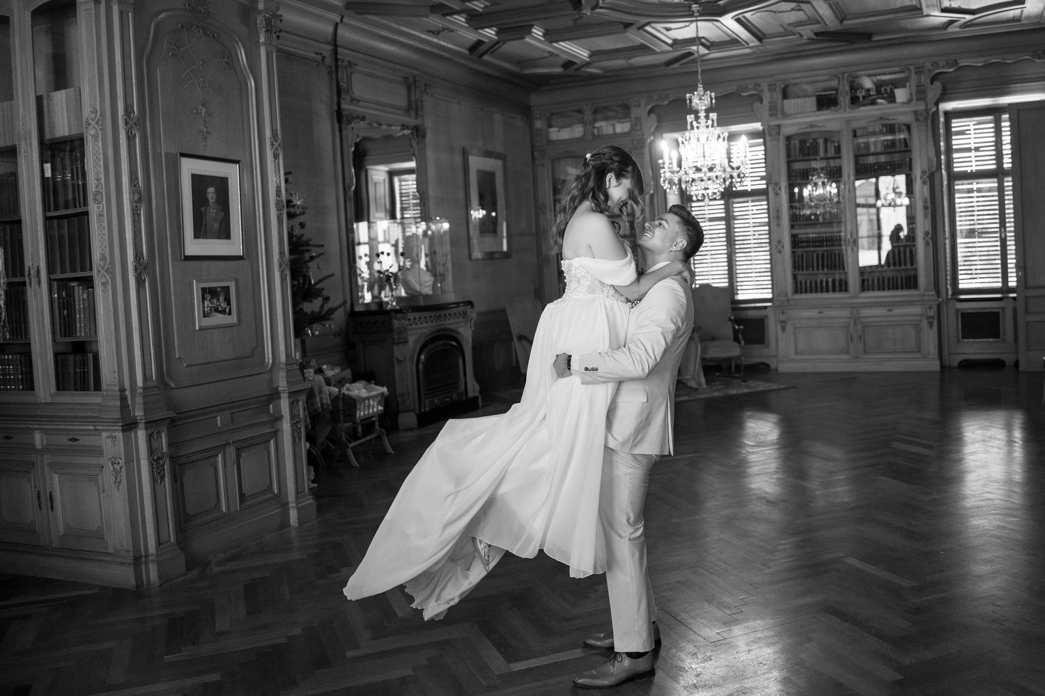 A couple sharing intimate moments in an elegant ballroom with wooden details.
