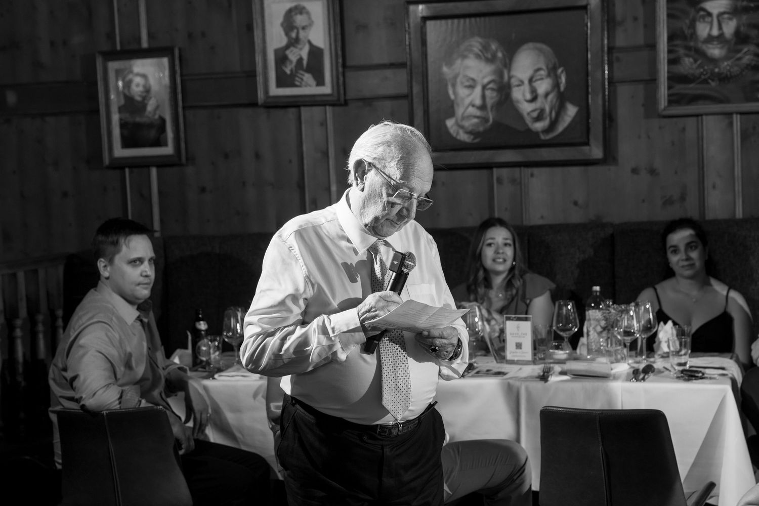 Black and white photo of guests dining at tables during a formal reception.