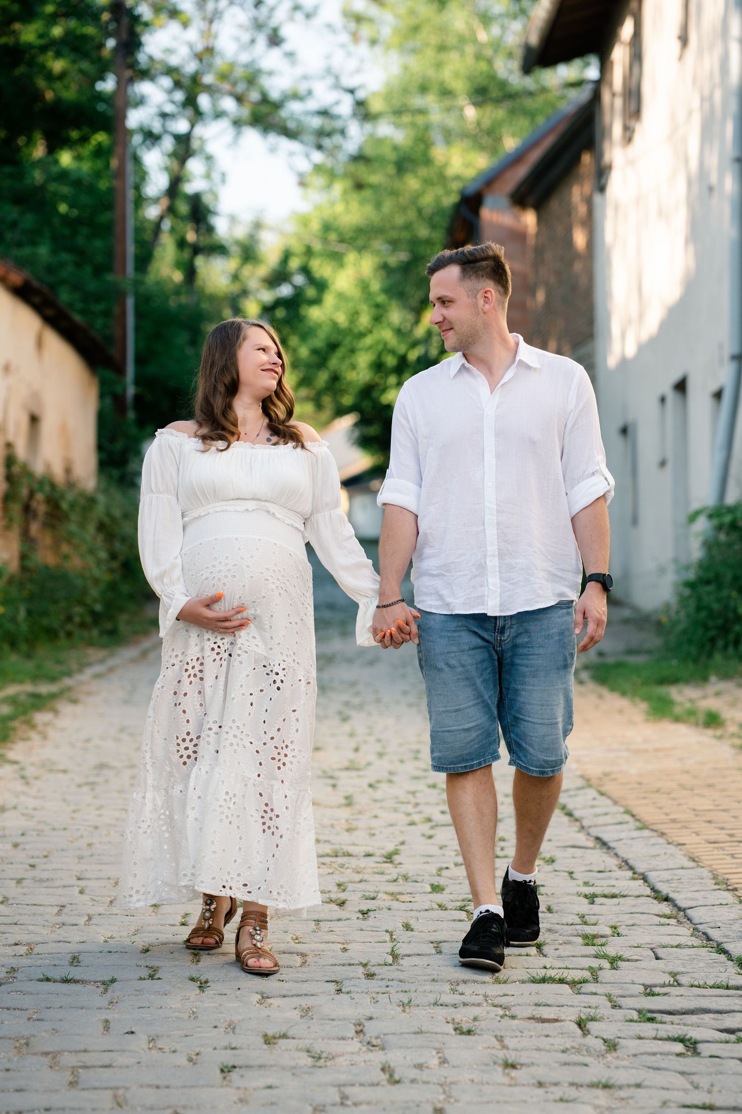 Couple walking hand in hand on a cobblestone path in a romantic outdoor setting.