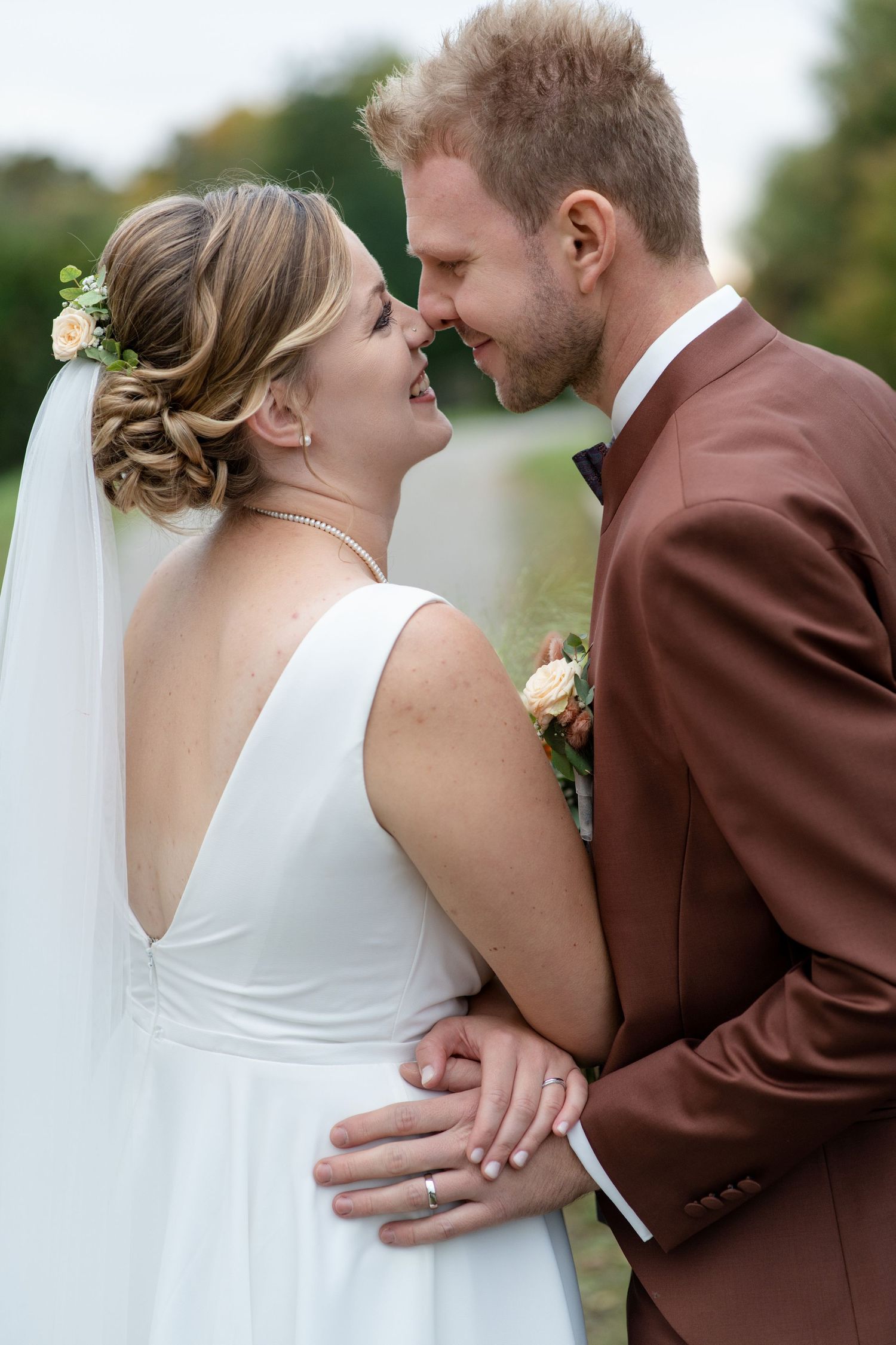 Close-up of a tender moment between a couple in wedding attire outdoors.