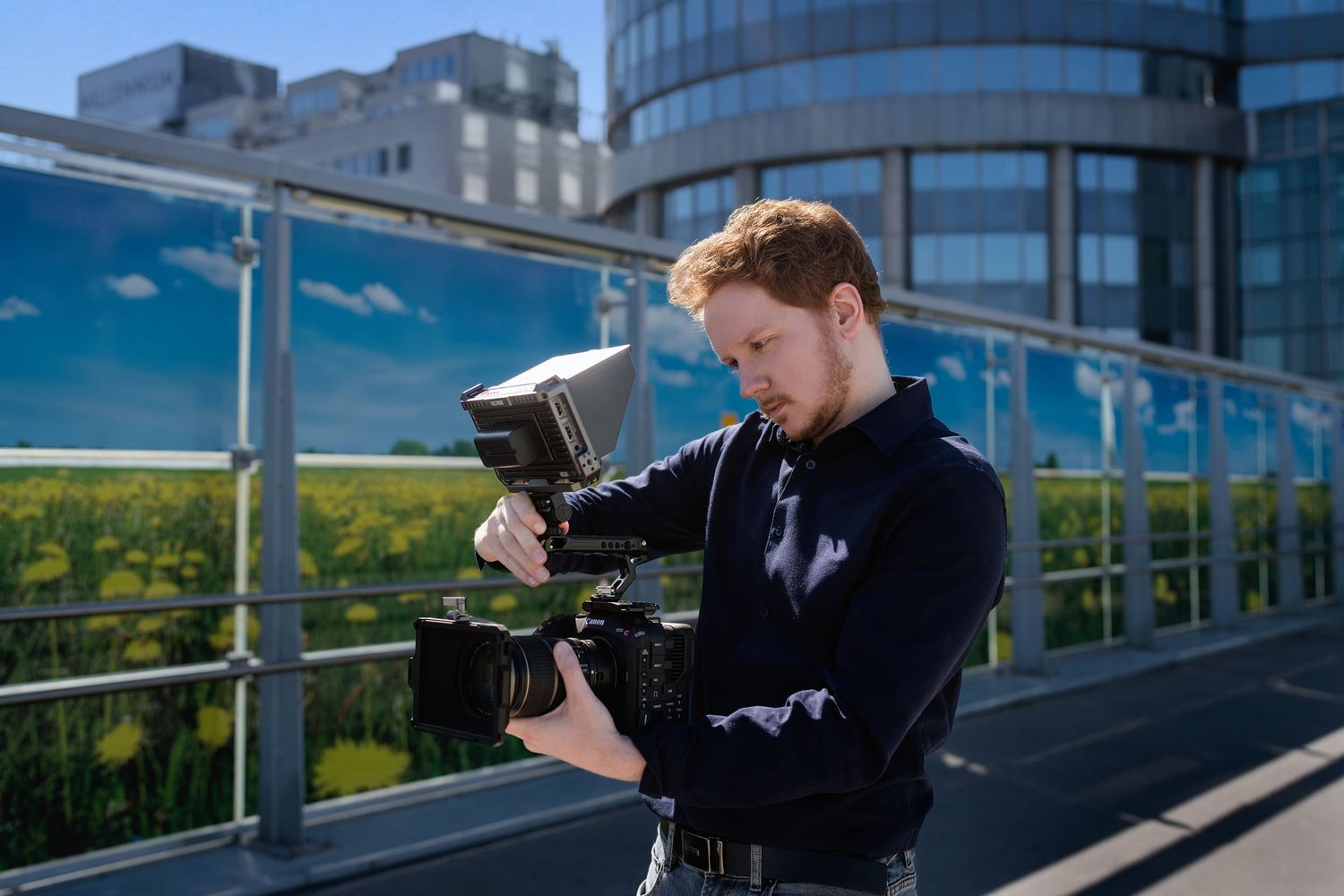 Professional photographer capturing shots from multiple angles on a modern building rooftop terrace with cityscape views.
