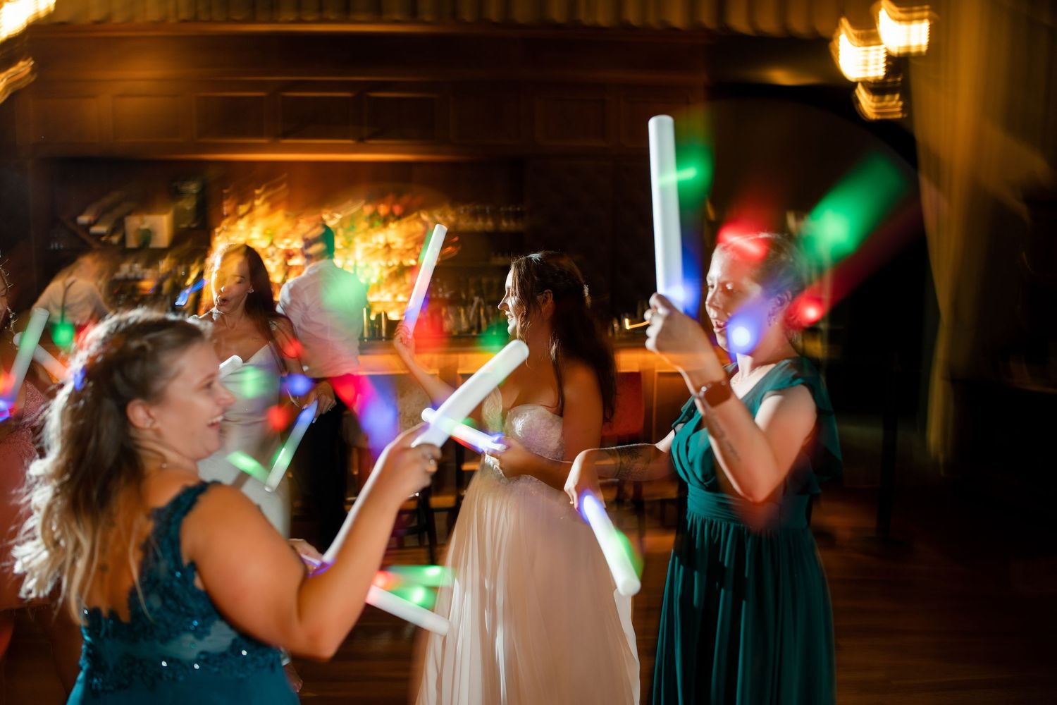 Wedding guests celebrate on the dance floor with glowing LED foam sticks.