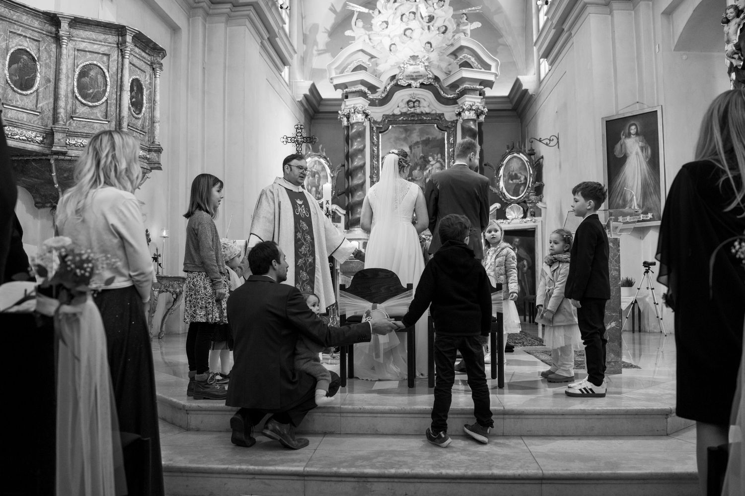 Wide view of a grand church interior during a wedding ceremony with guests standing.
