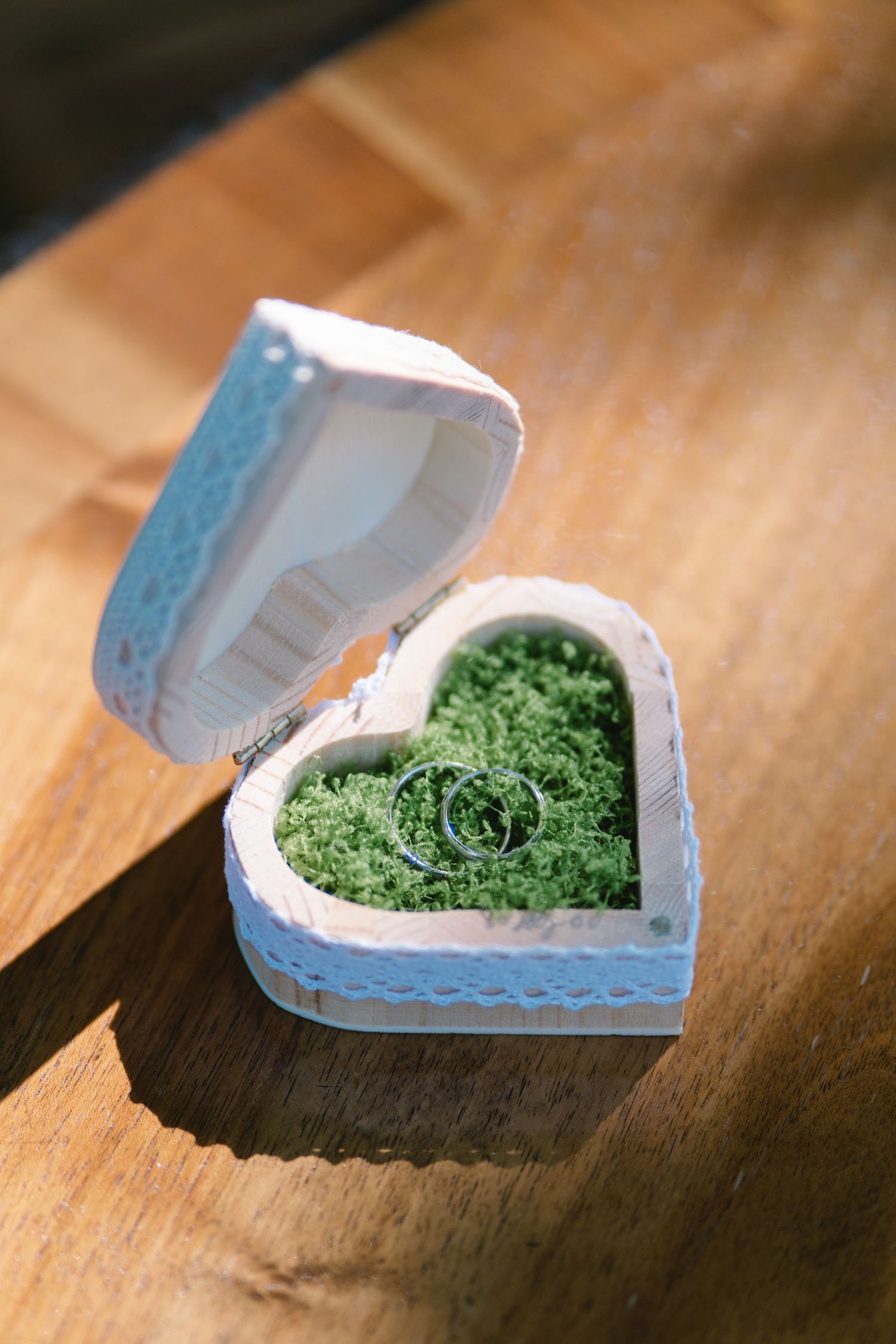 Heart-shaped box filled with preserved green moss on wooden surface.
