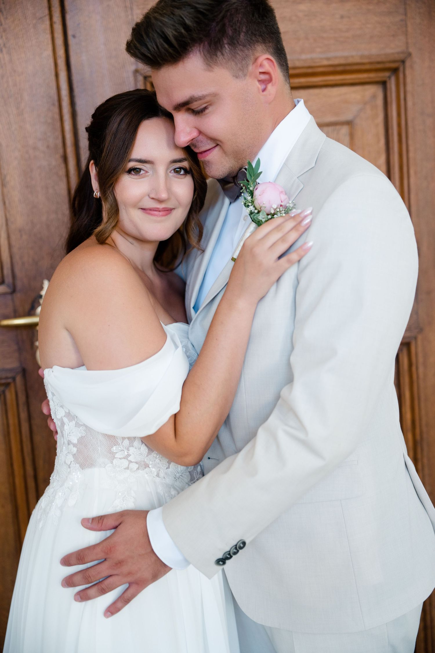 Intimate wedding portrait of couple embracing against wooden door background.
